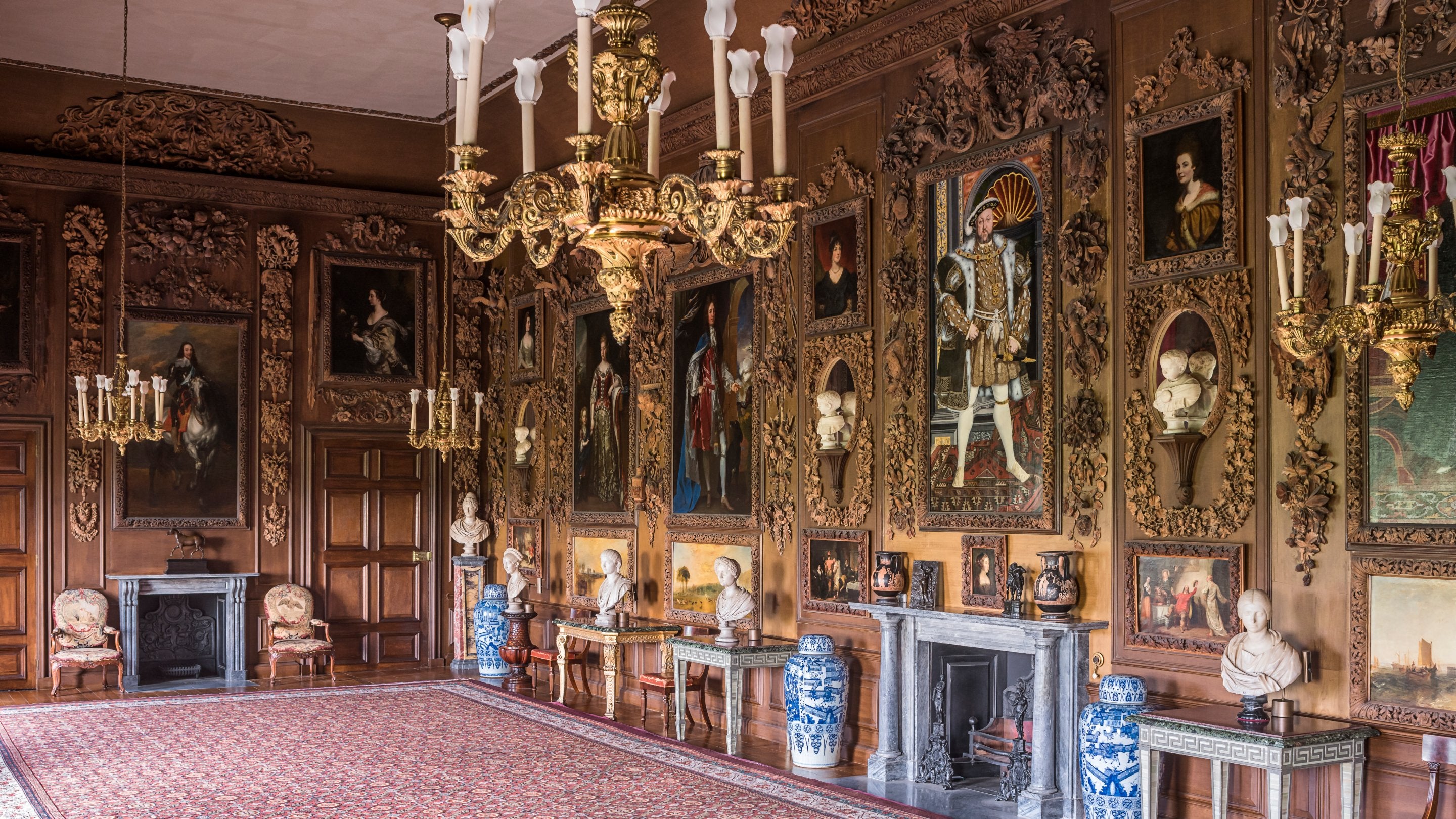 The Carved Room, with the four paintings by Turner restored to the panelling, looking south at Petworth House and Park, West Sussex, with carvings by Grinling Gibbons, and a Henry VIII portrait hanging over the fireplace.
