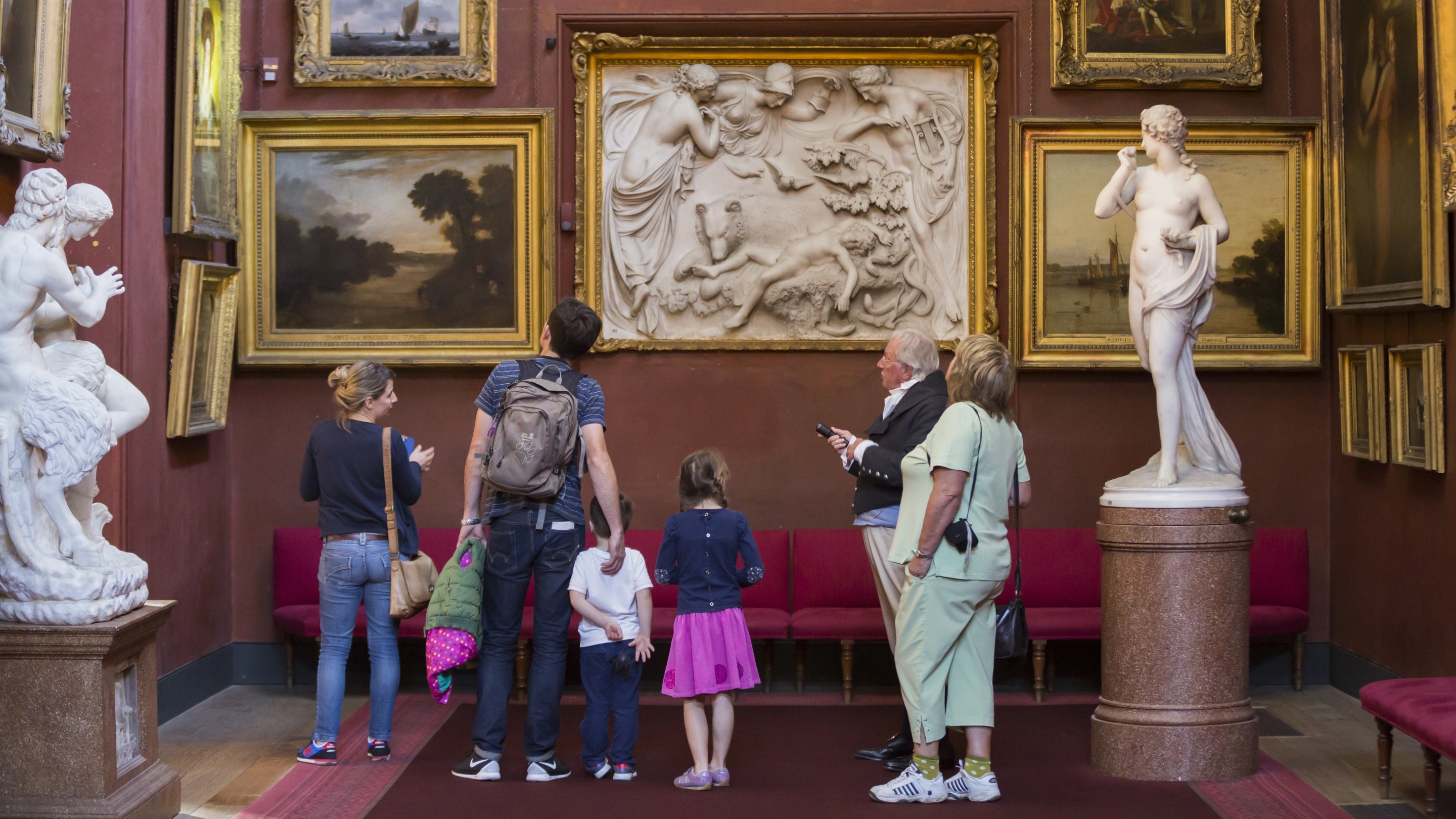 Family talking to a room guide in the North Gallery, Petworth House and Park, West Sussex