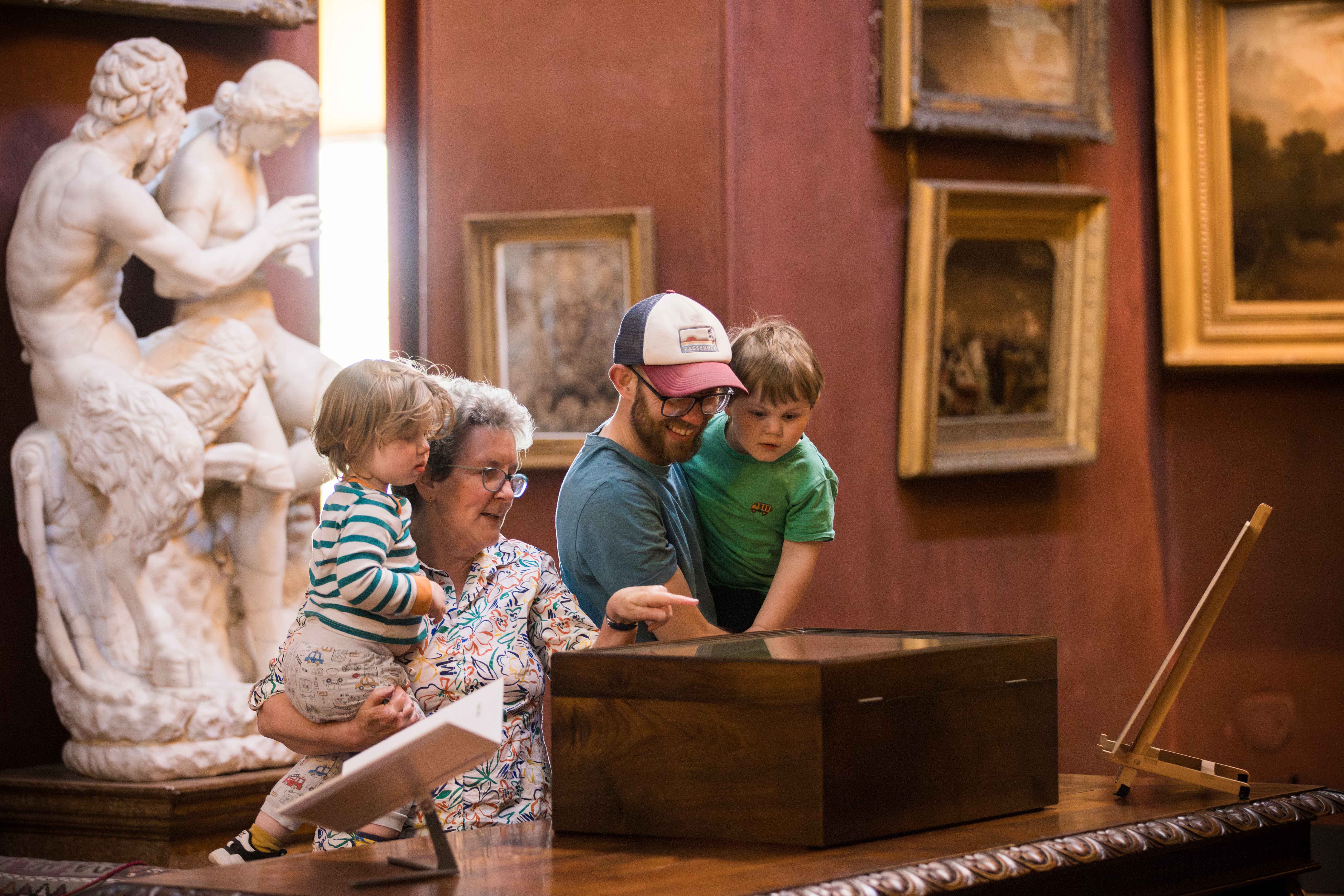 A family exploring the collection in the North Gallery at Petworth House, West Sussex