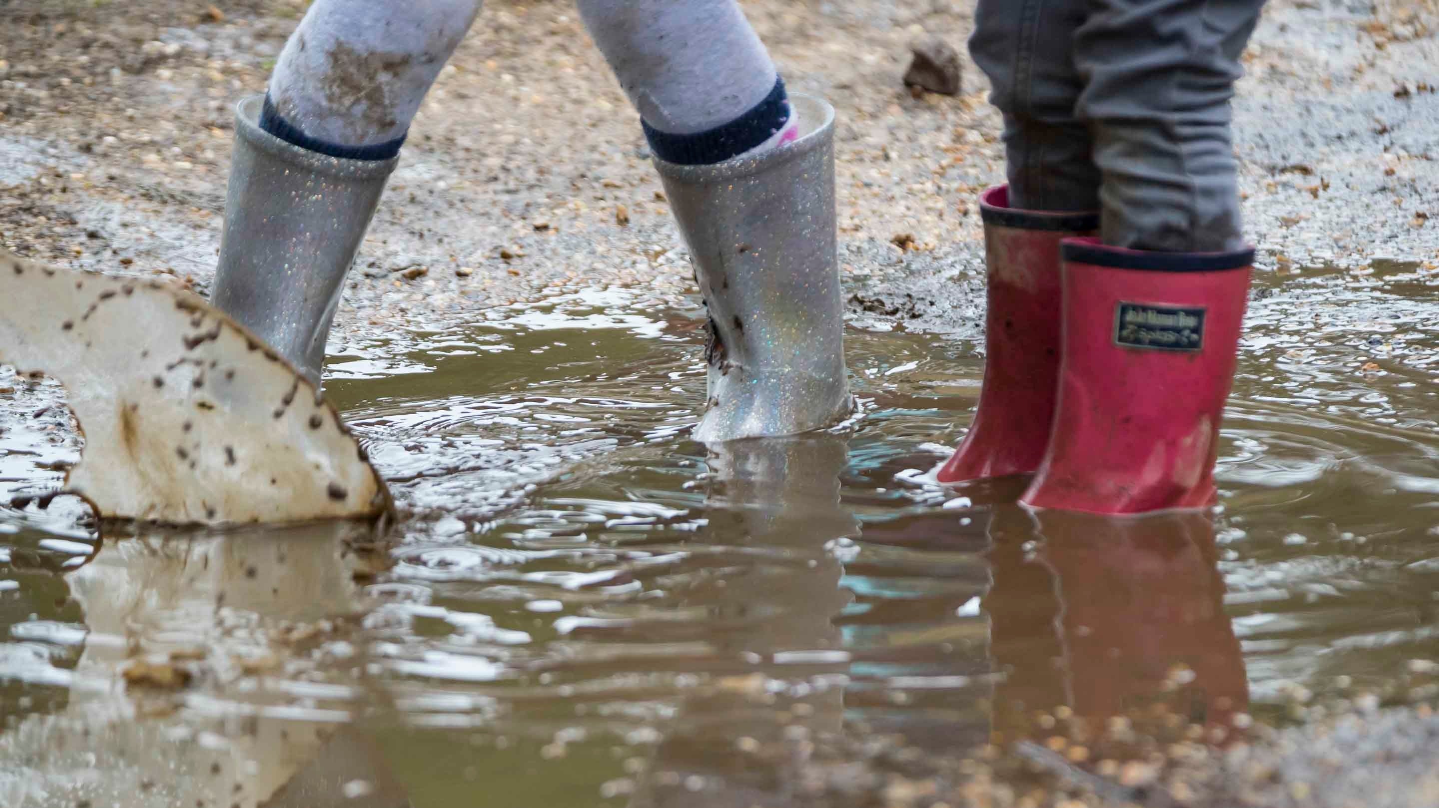 Children's feet in wellington boots  jumping in puddles at Sheffield Park, East Sussex