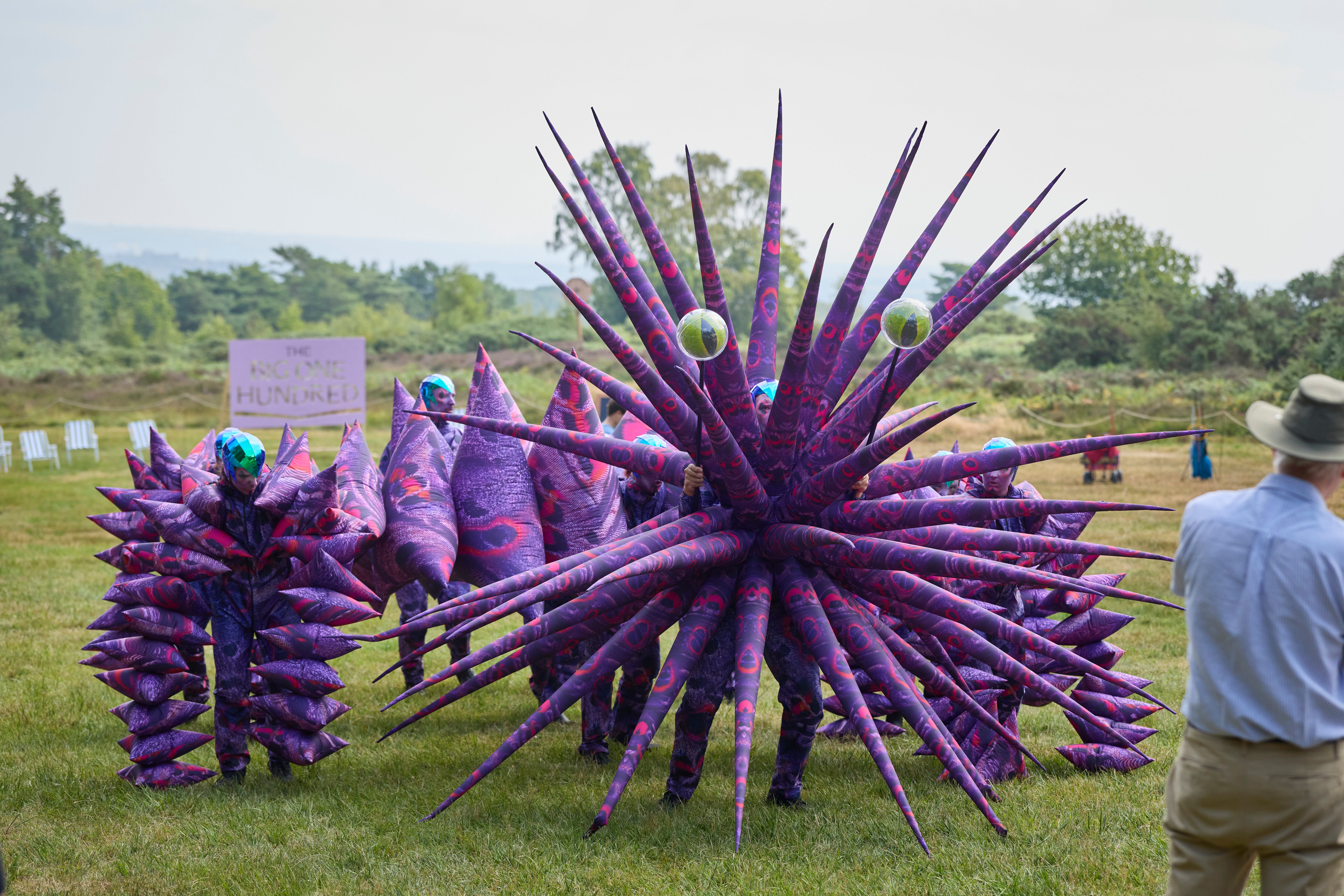 Giant puppet with spiky purple and pink body and giant green eyes.