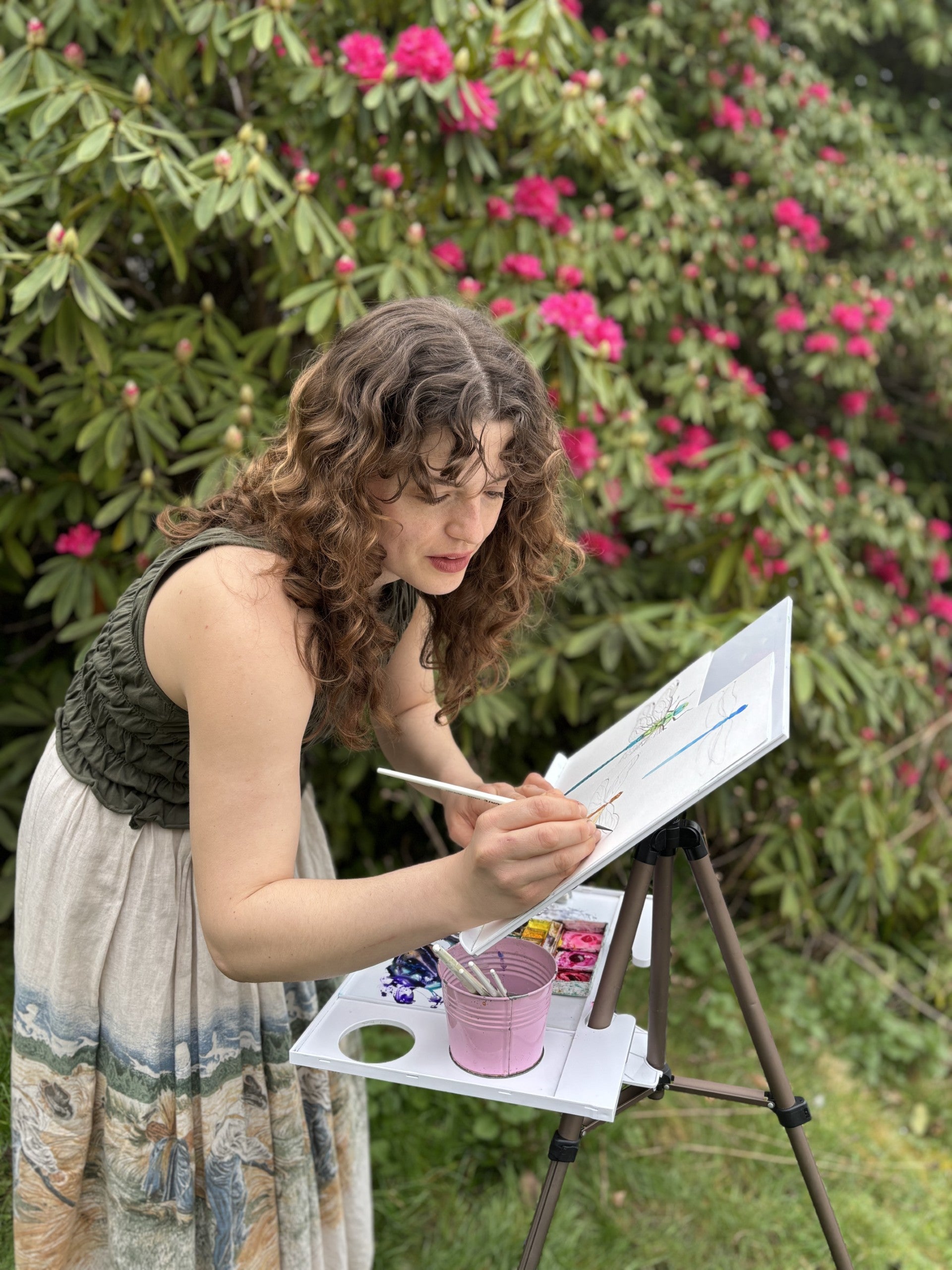 A women with an easel and watercolour painting outdoors