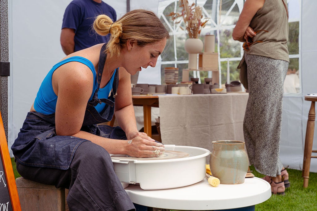 Woman moulding pottery in a marquee as part of a maker's fair