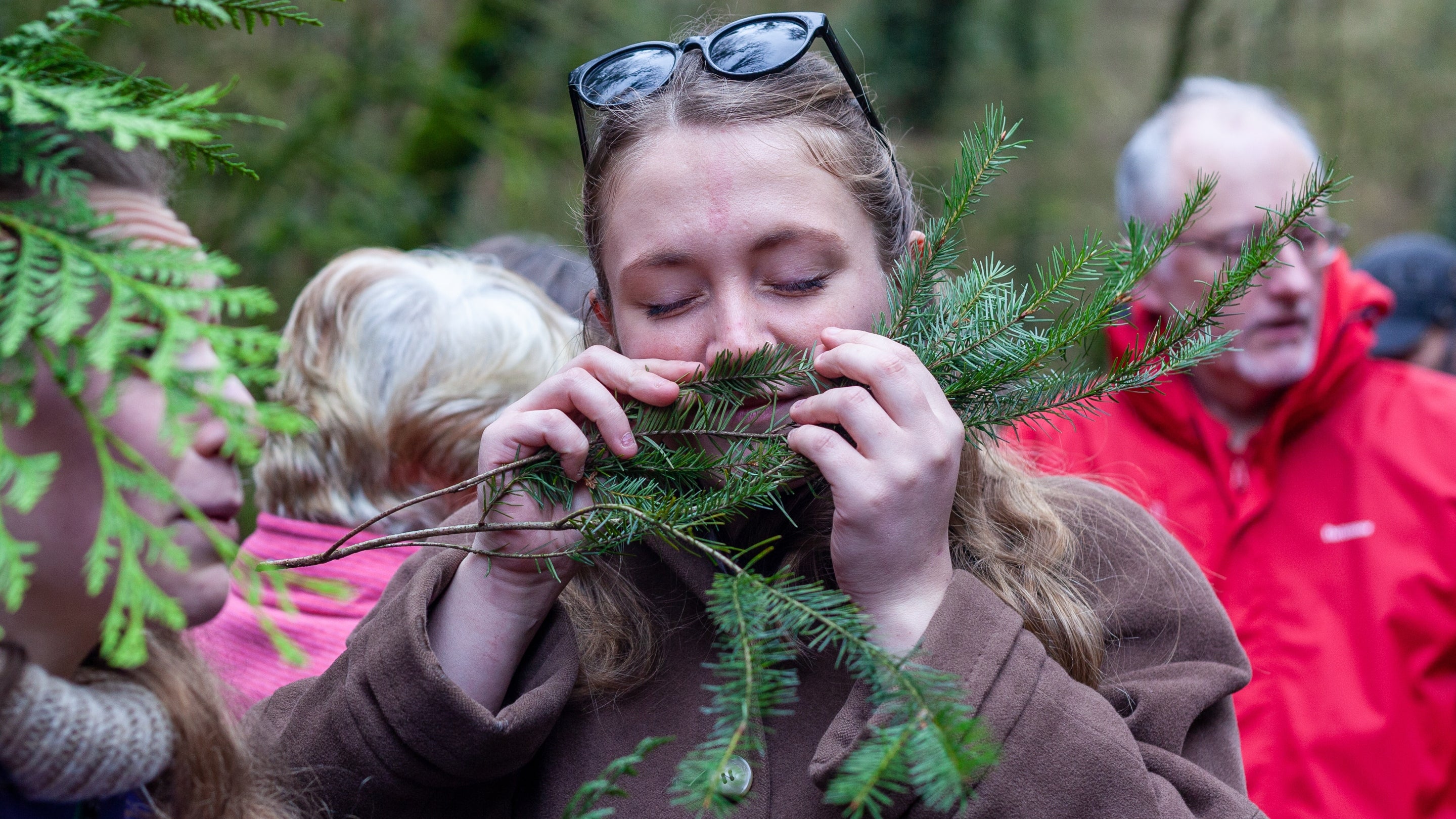 A woman smelling the leaves of a tree on a forest bathing session