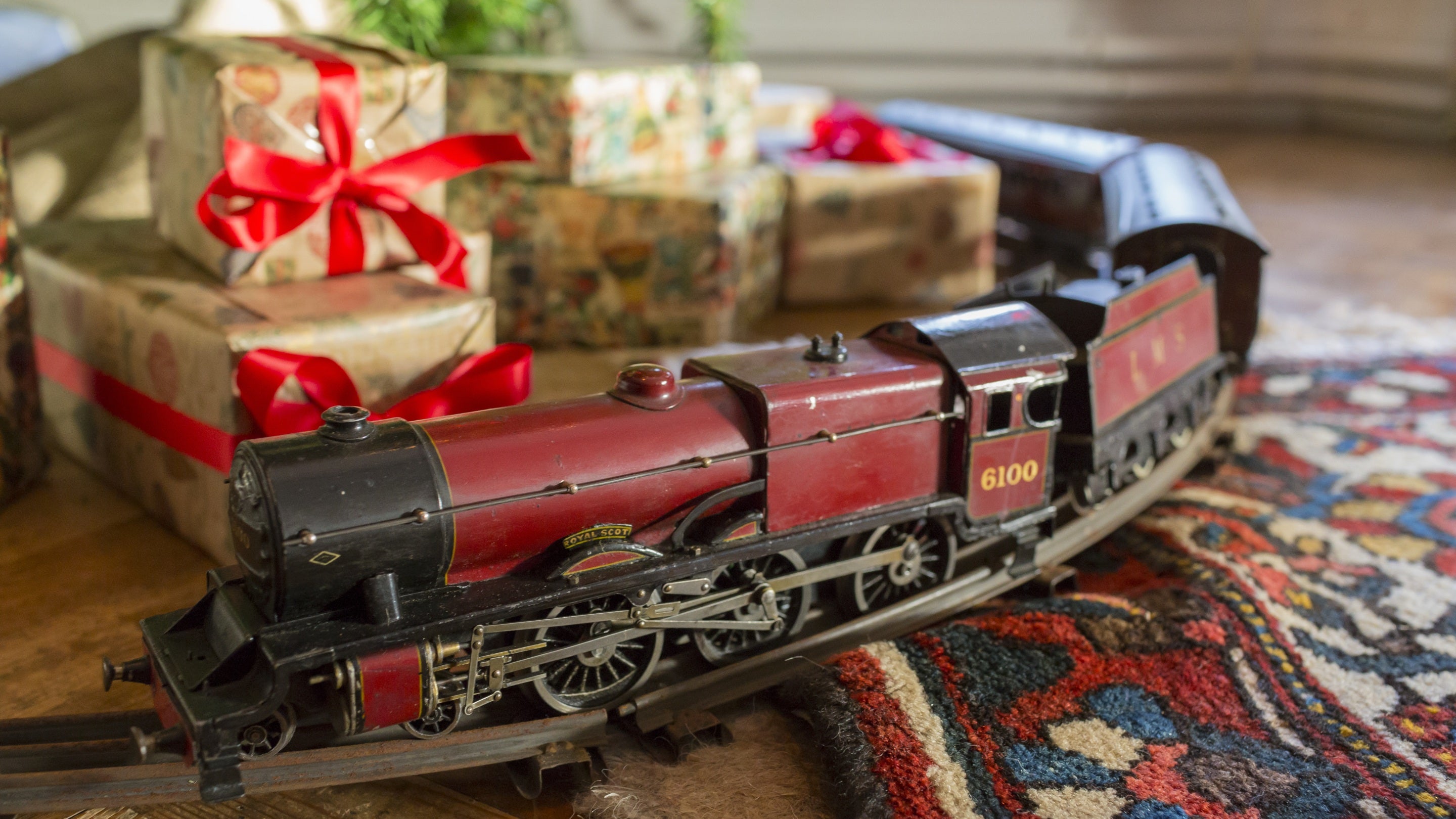 Christmas gifts and an old-fashioned model train on a circular track, on the floor of a room at Standen House and Garden, West Sussex.