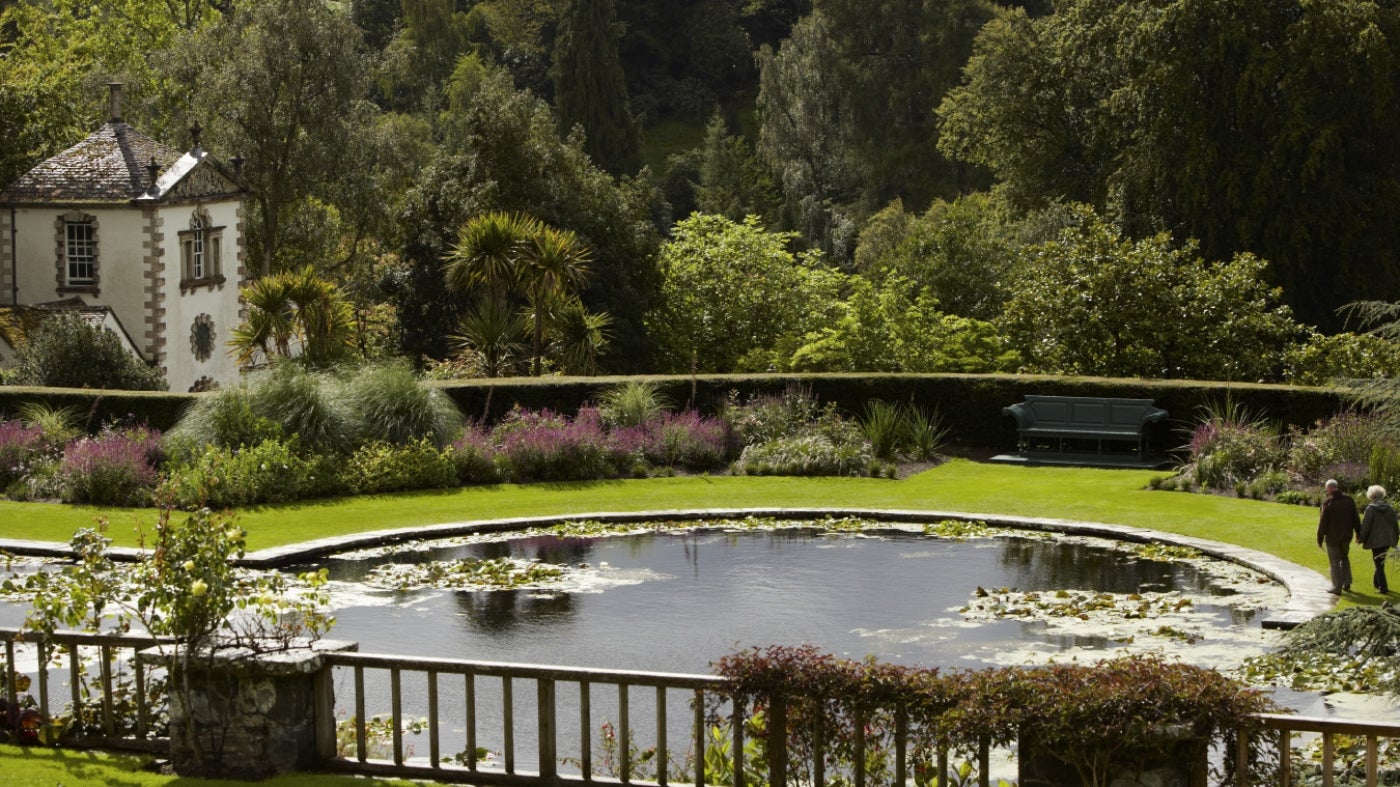 A view of the Lily Terrace and pond, with a glimpse of Pin Mill beyond at Bodnant Garden, Conwy, Wales