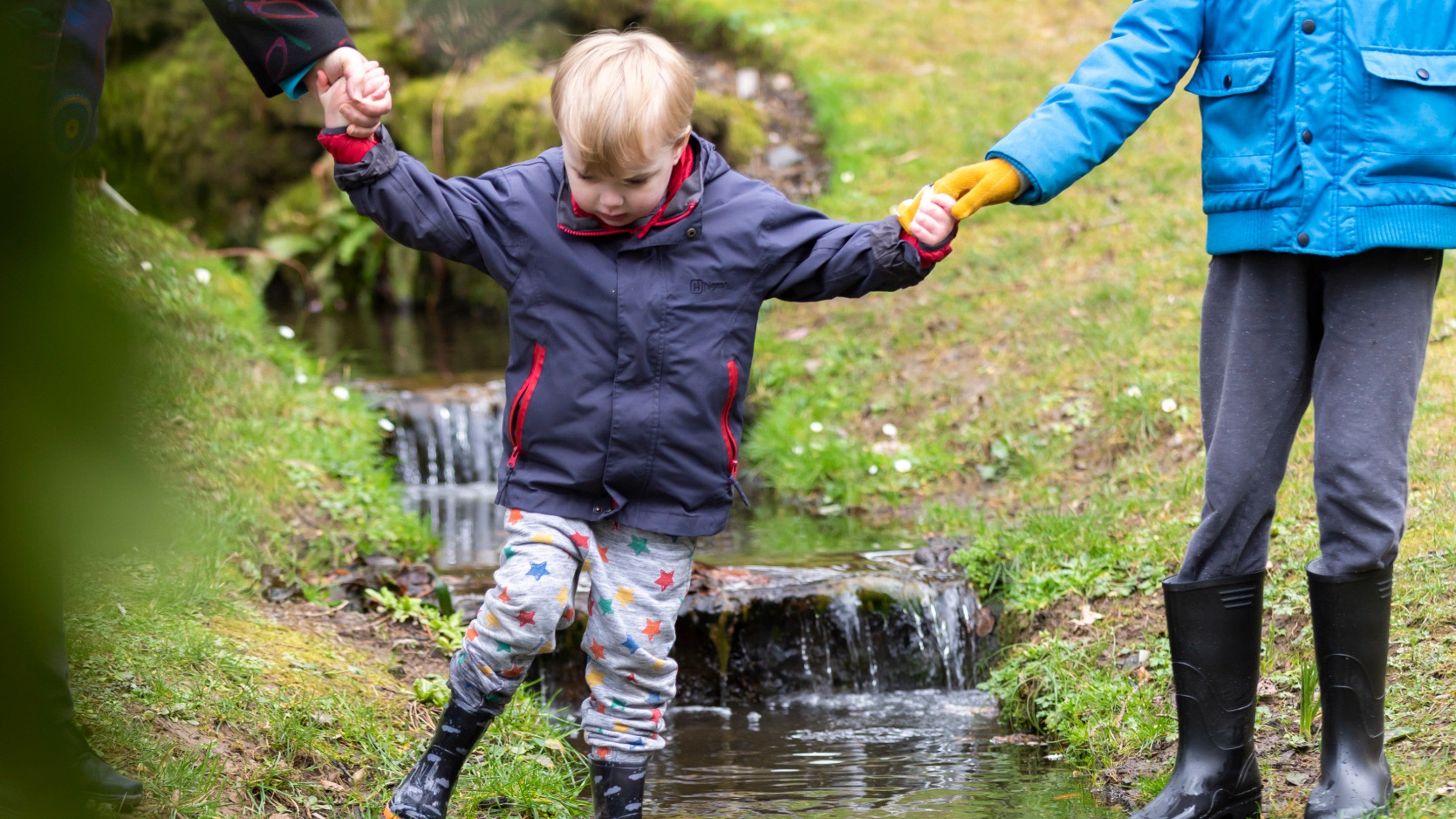 Visitors walking by the stream at Bodnant Garden, North Wales