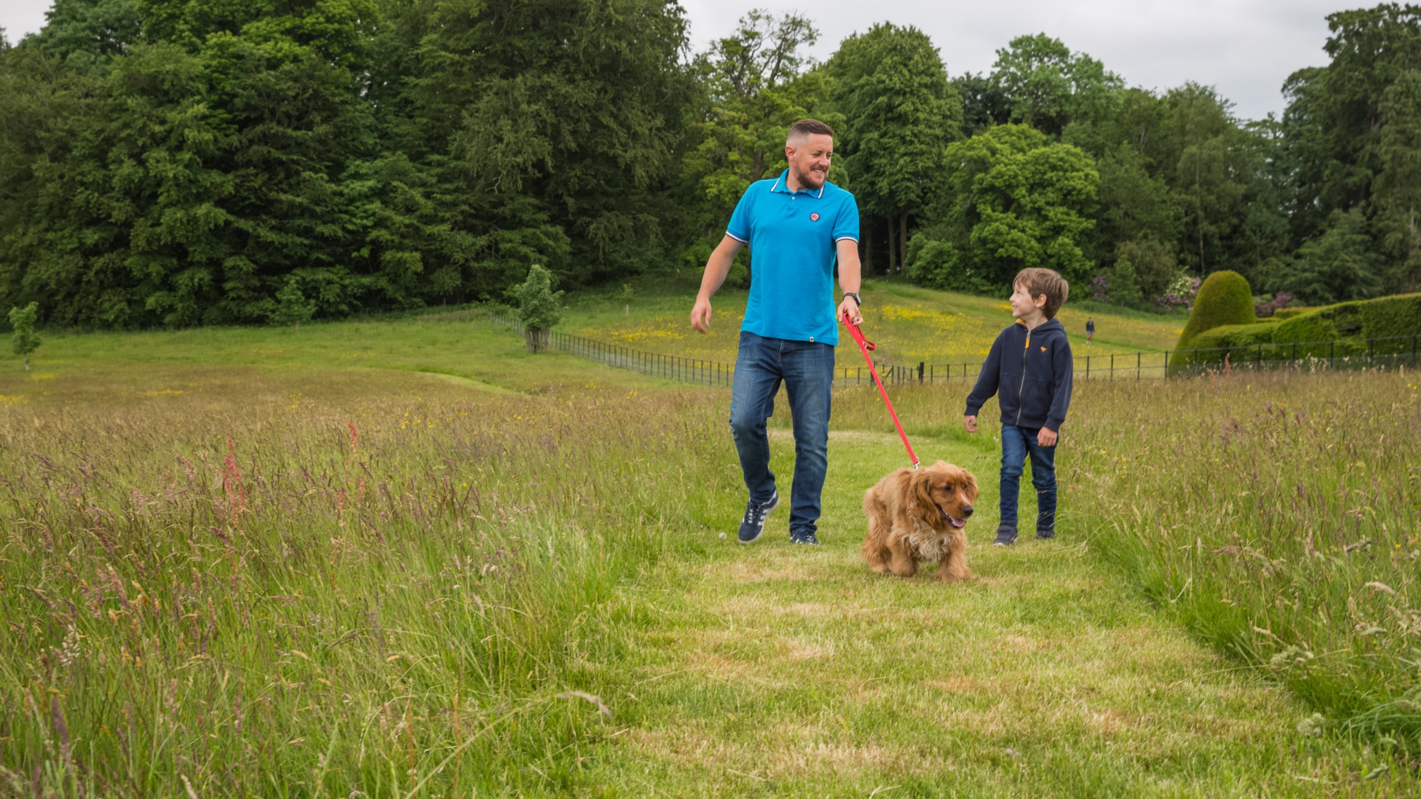 Visitors walking their dog in the parkland at Chirk Castle, Wrexham