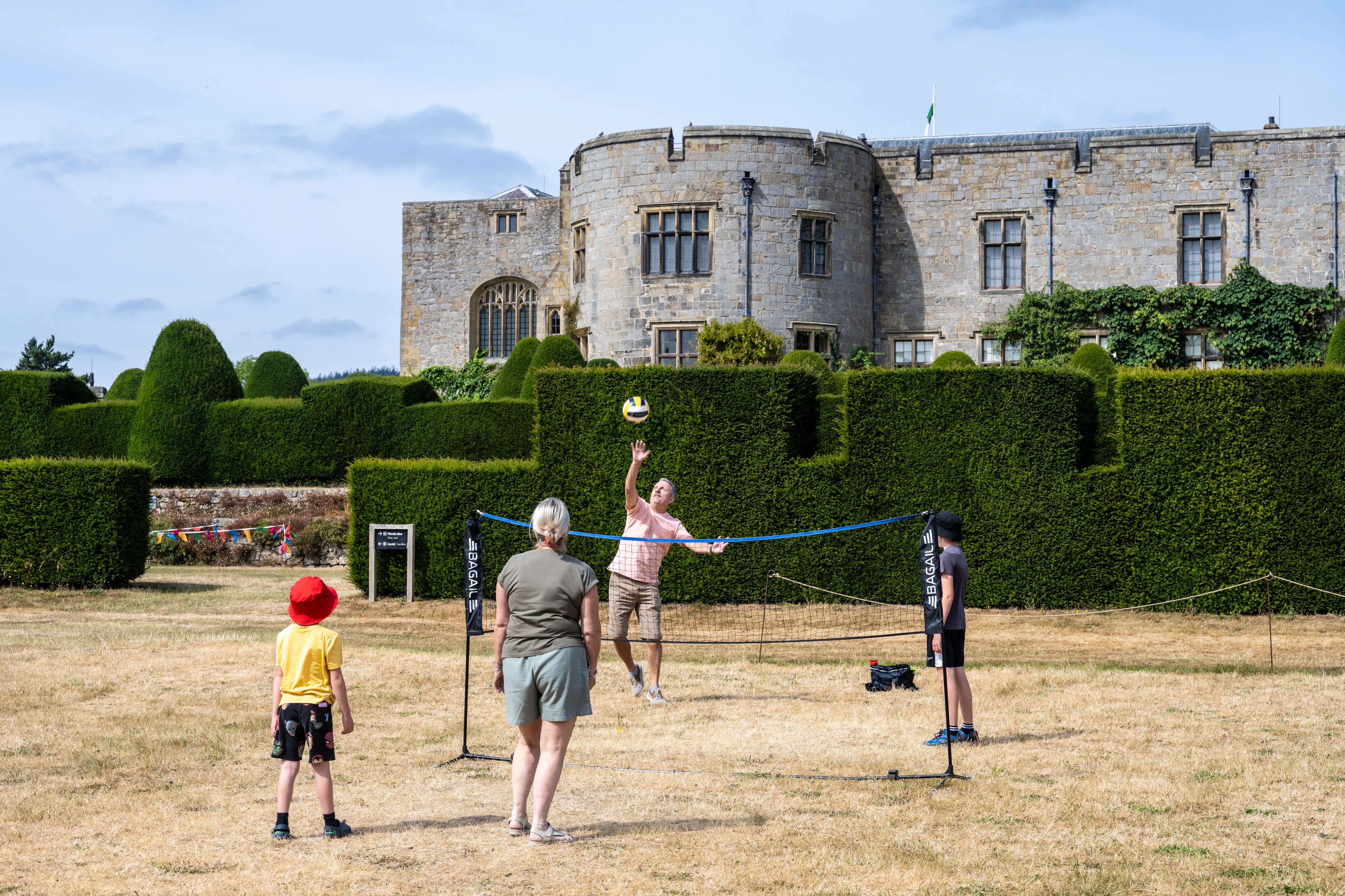 A family playing volleyball on the lawn in front of Chirk Castle.