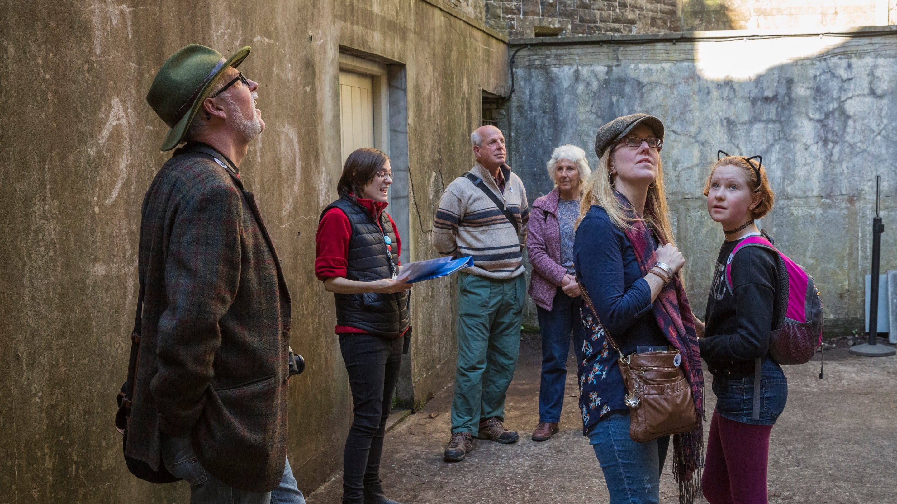 Visitors on a guided tour look around an enclosed outdoor space at Dinefwr, Carmarthenshire, Wales