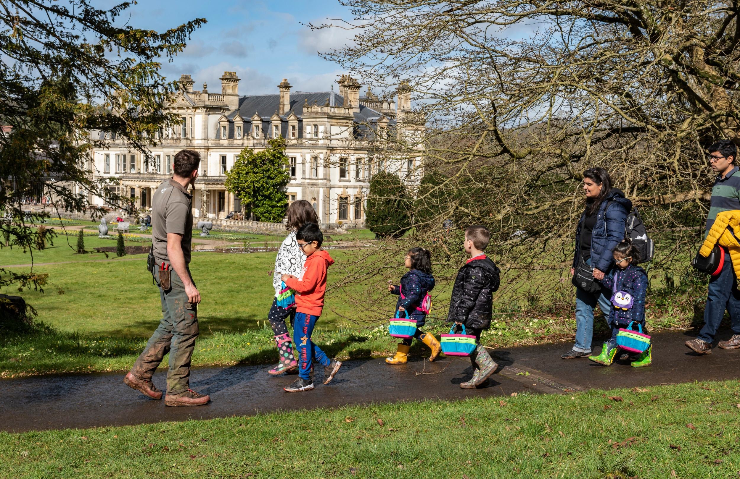 The Head Gardener shows a group of adults and children round Dyffryn Gardens with Dyffryn House in the background