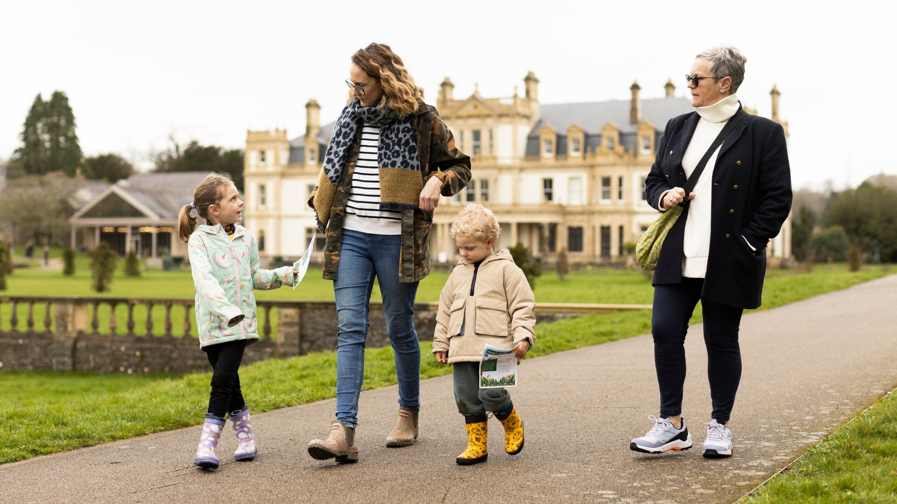A family dressed for winter walk along a path with a house behind them