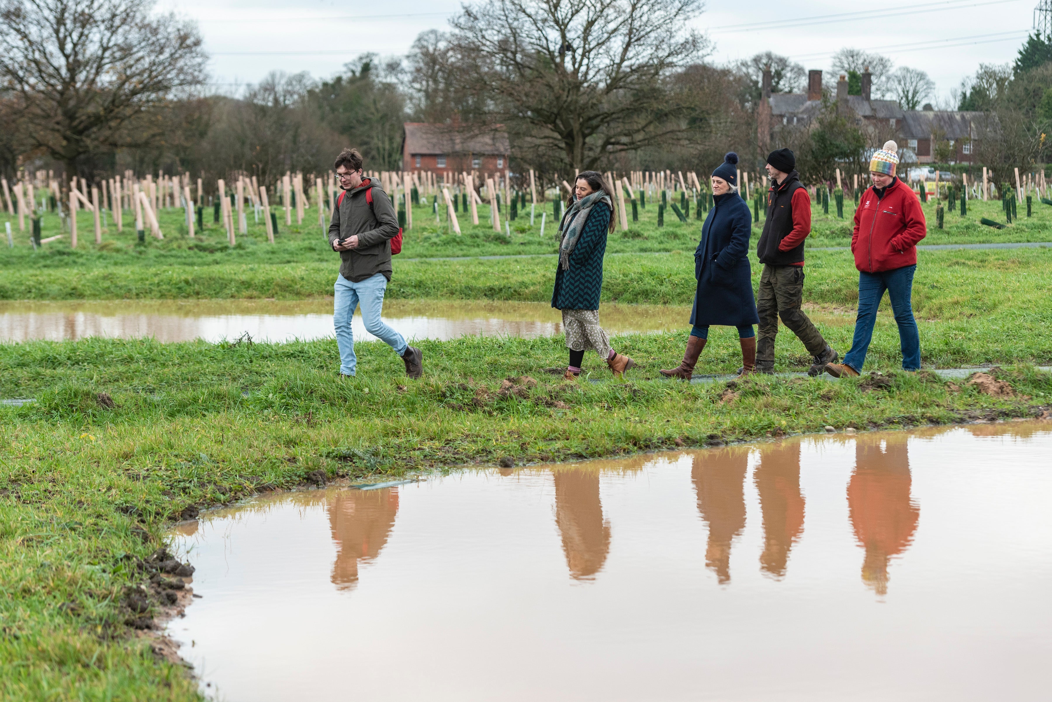 A group of people walking around a pond in the Commemorative Woodland at Erddig.