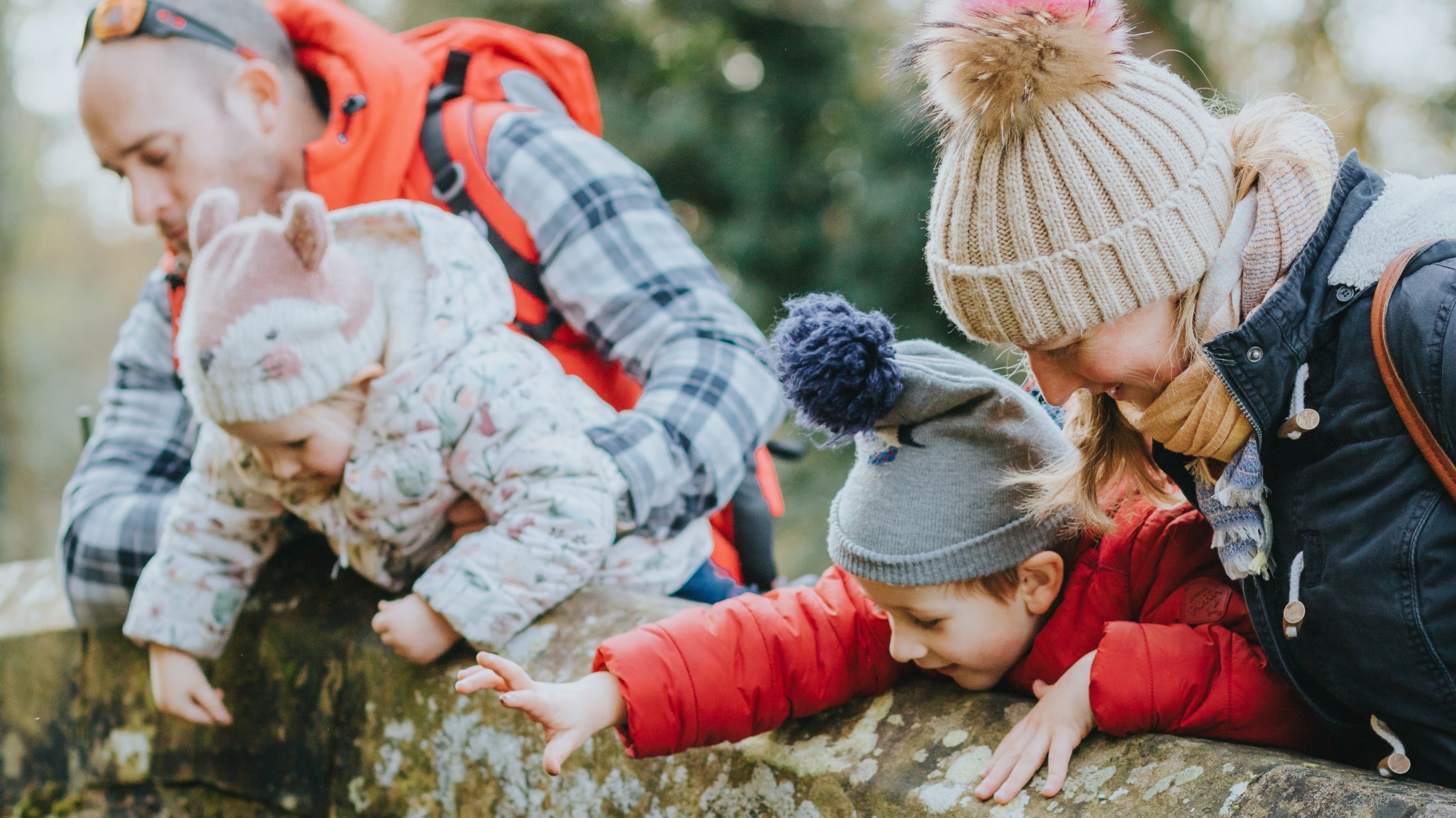 Family playing pooh sticks on a stone bridge at Erddig in Wales