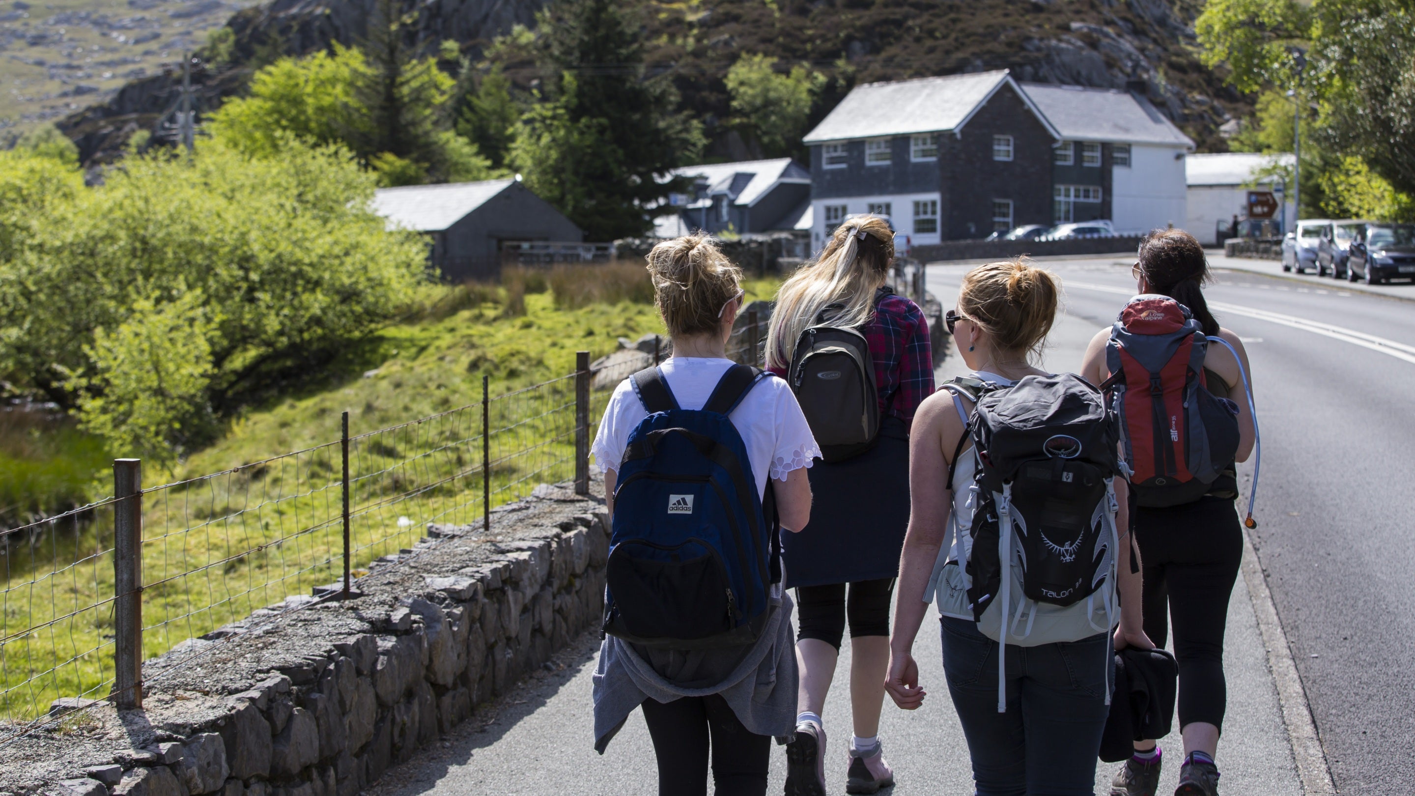 Visitors with rucksacks walking towards Ogwen Cottage on a sunny day, Carneddau and Glyderau, Gwynedd, Wales