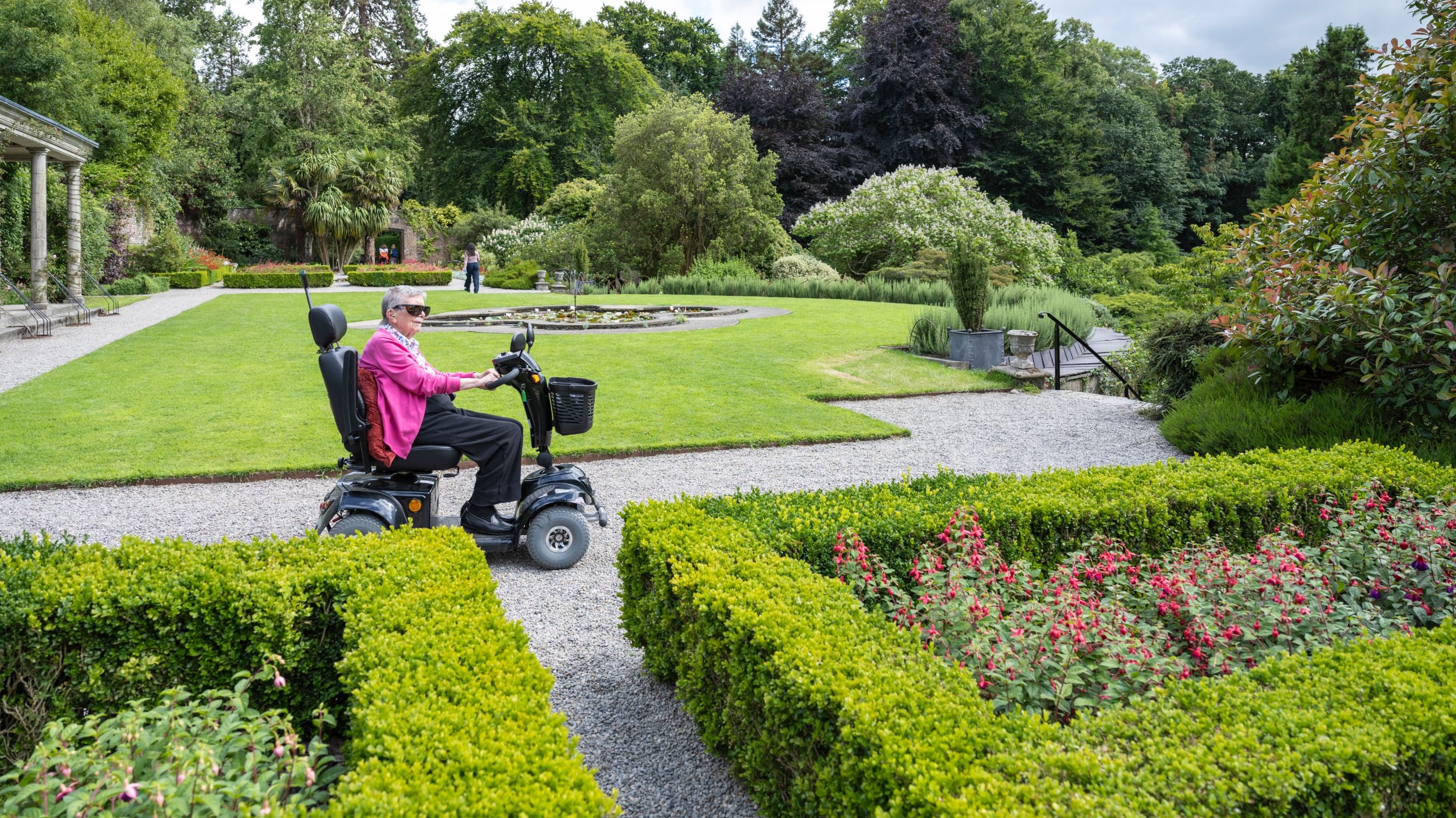 A visitor using a motorised scooter enjoys the Walled Garden at Penrhyn Castle