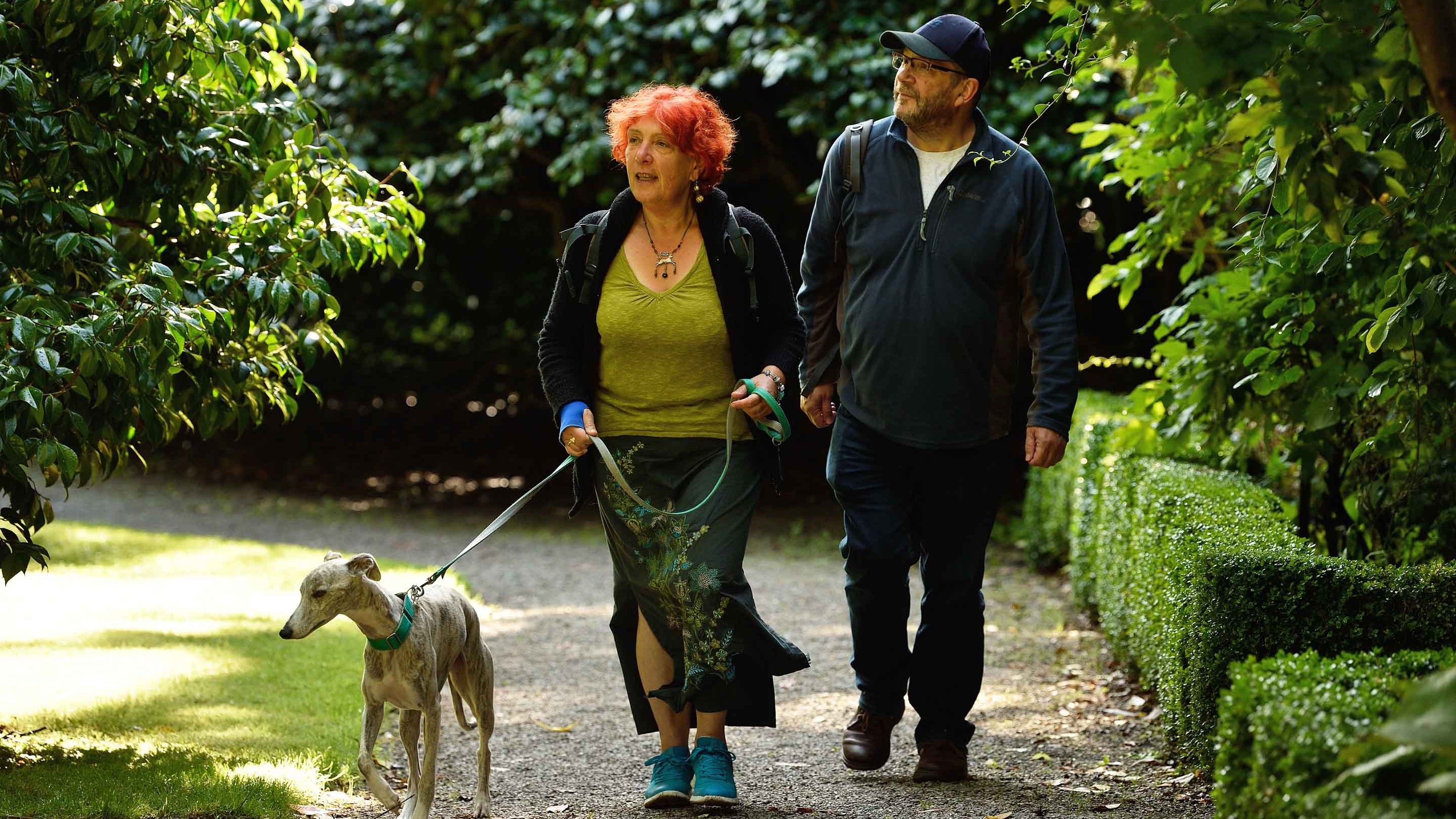 Visitors walking with their dog in the gardens at Penrhyn Castle, North Wales