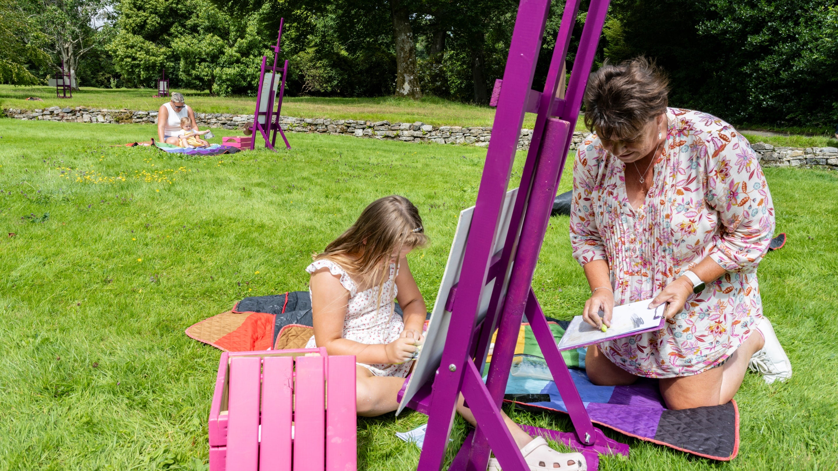 Family time on the lawn together, sitting in front of a purple easel drawing together