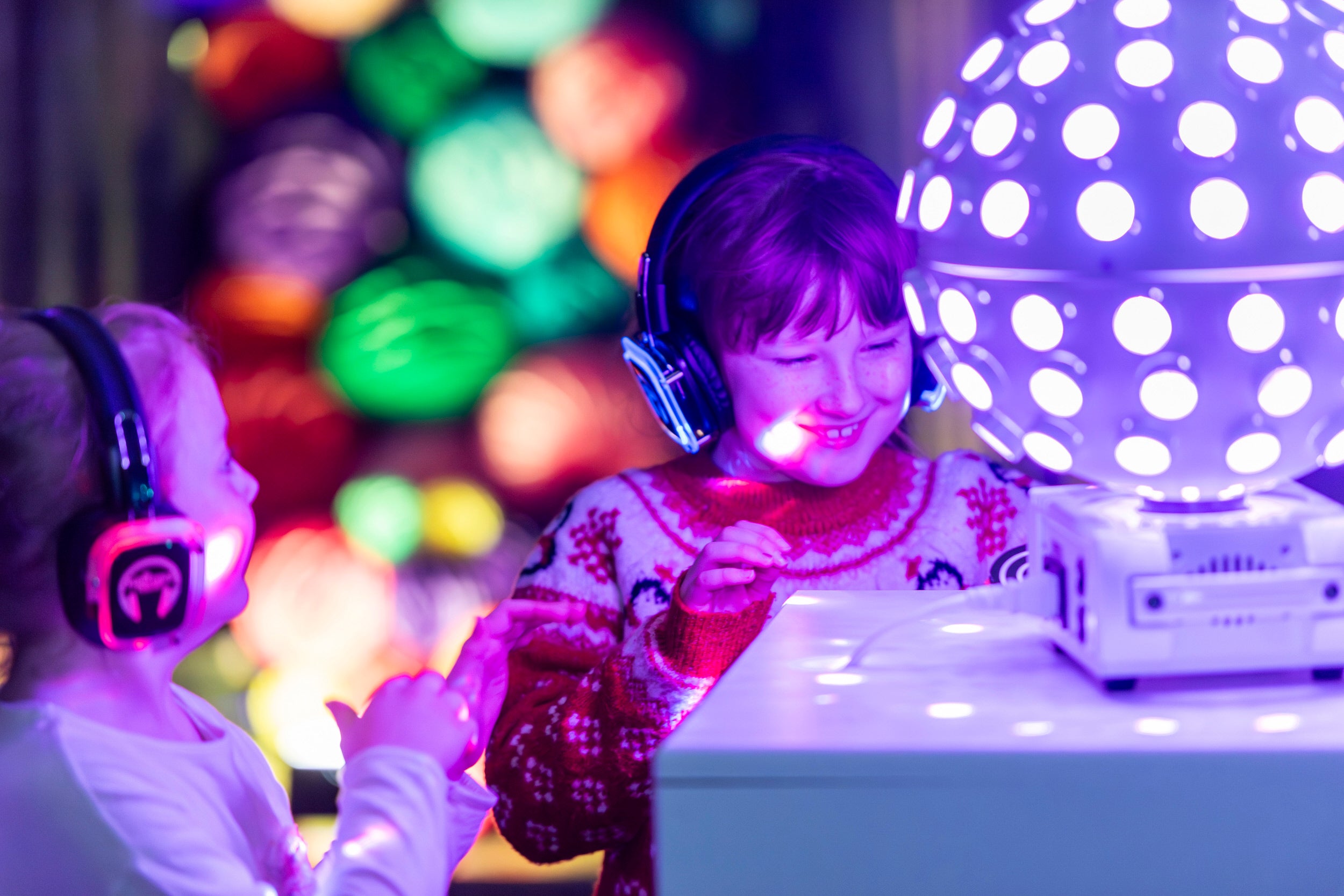 Young children looking into illuminating disco ball at  silent disco in the Music Room at Plas Newydd House and Garden, Anglesey
