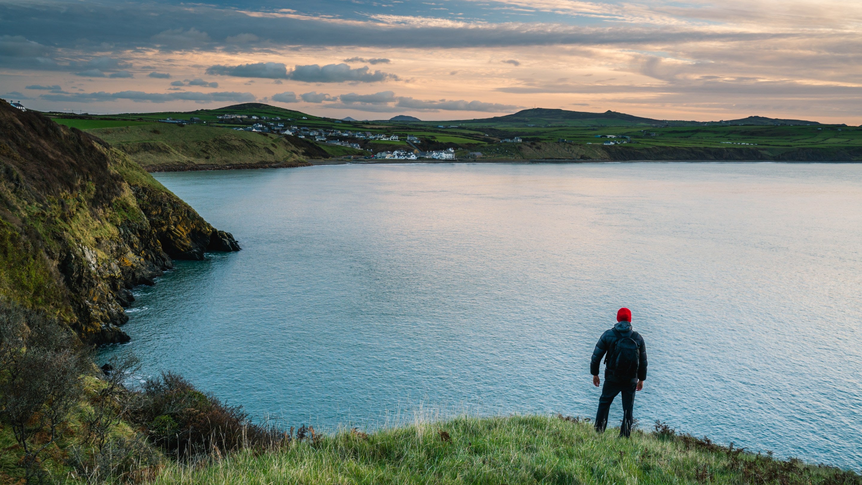 Person yn sefyll ar yr arfordir ym Mhorth Meudwy, Gwynedd