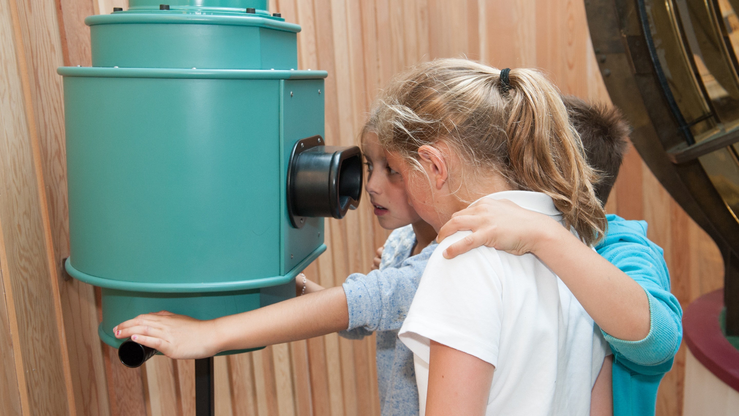 Three children are huddled around a periscope in 'The Light' exhibition at Porth y Swnt, Aberdaron, Gwynedd.