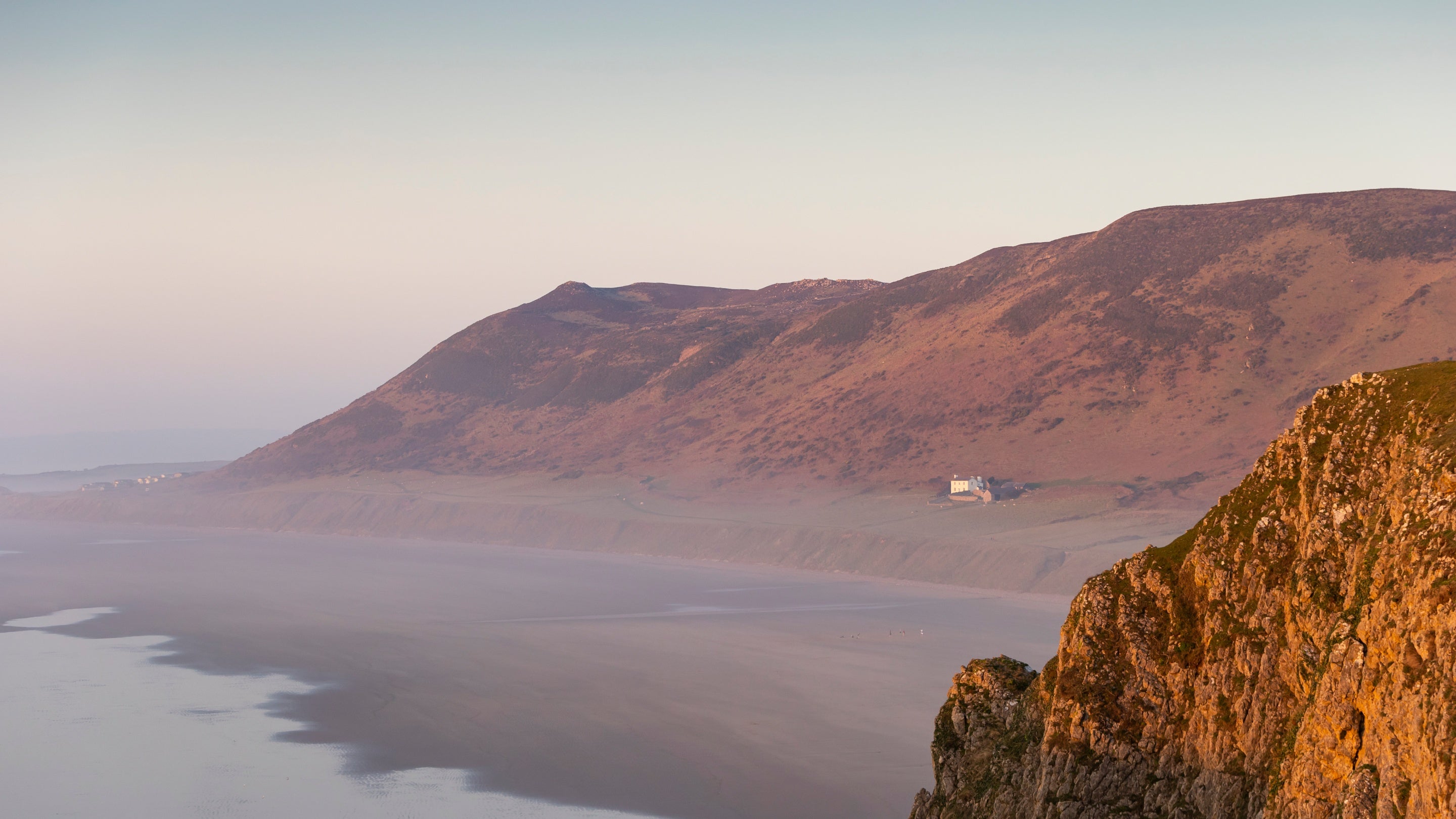 View of a tiny white cottage on the other side of a bay with hazy late autumn  light