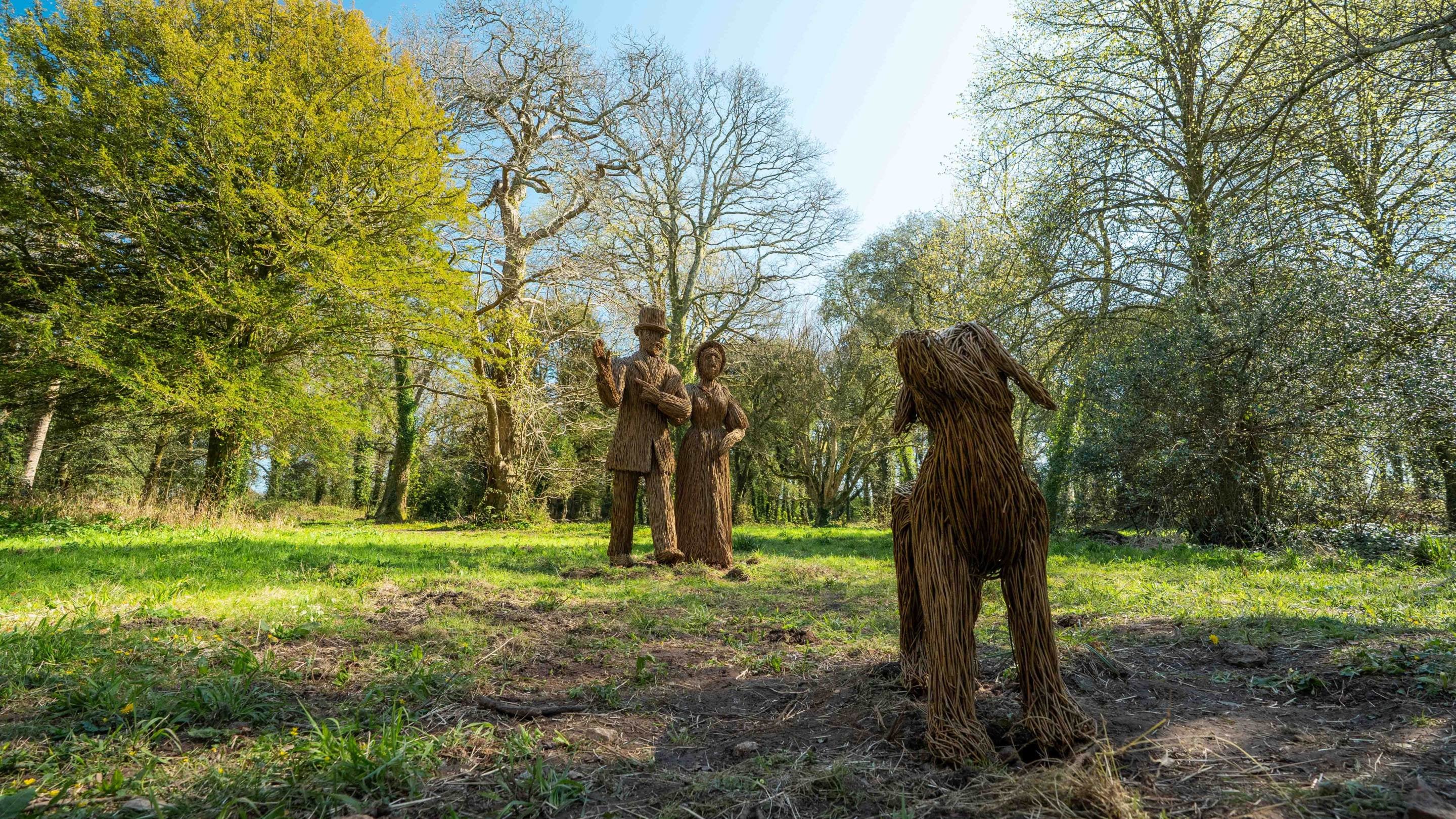 Cerfluniau helyg o ddau berson a chi