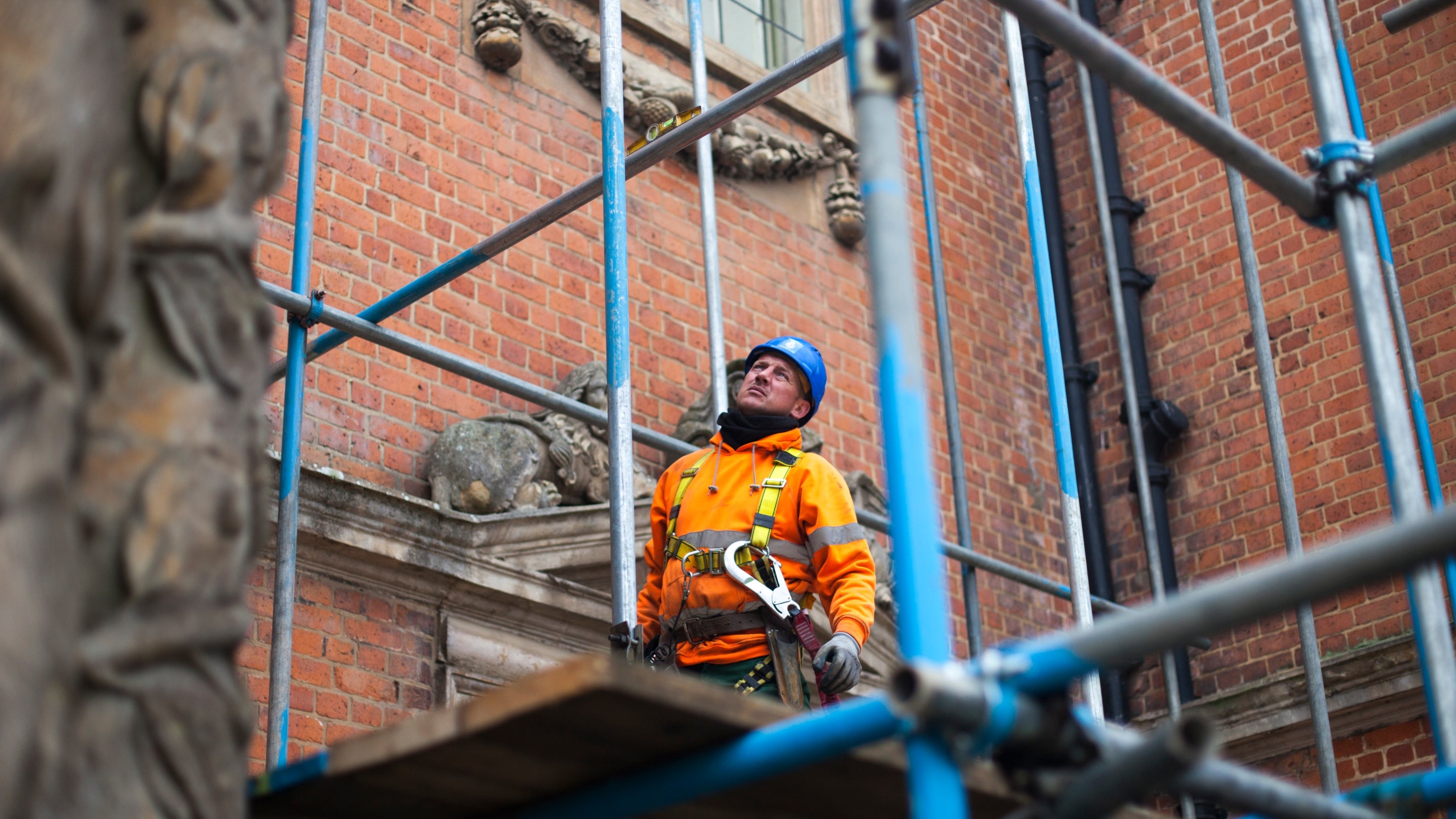 A builder assesses scaffolding on the front of Tredegar House