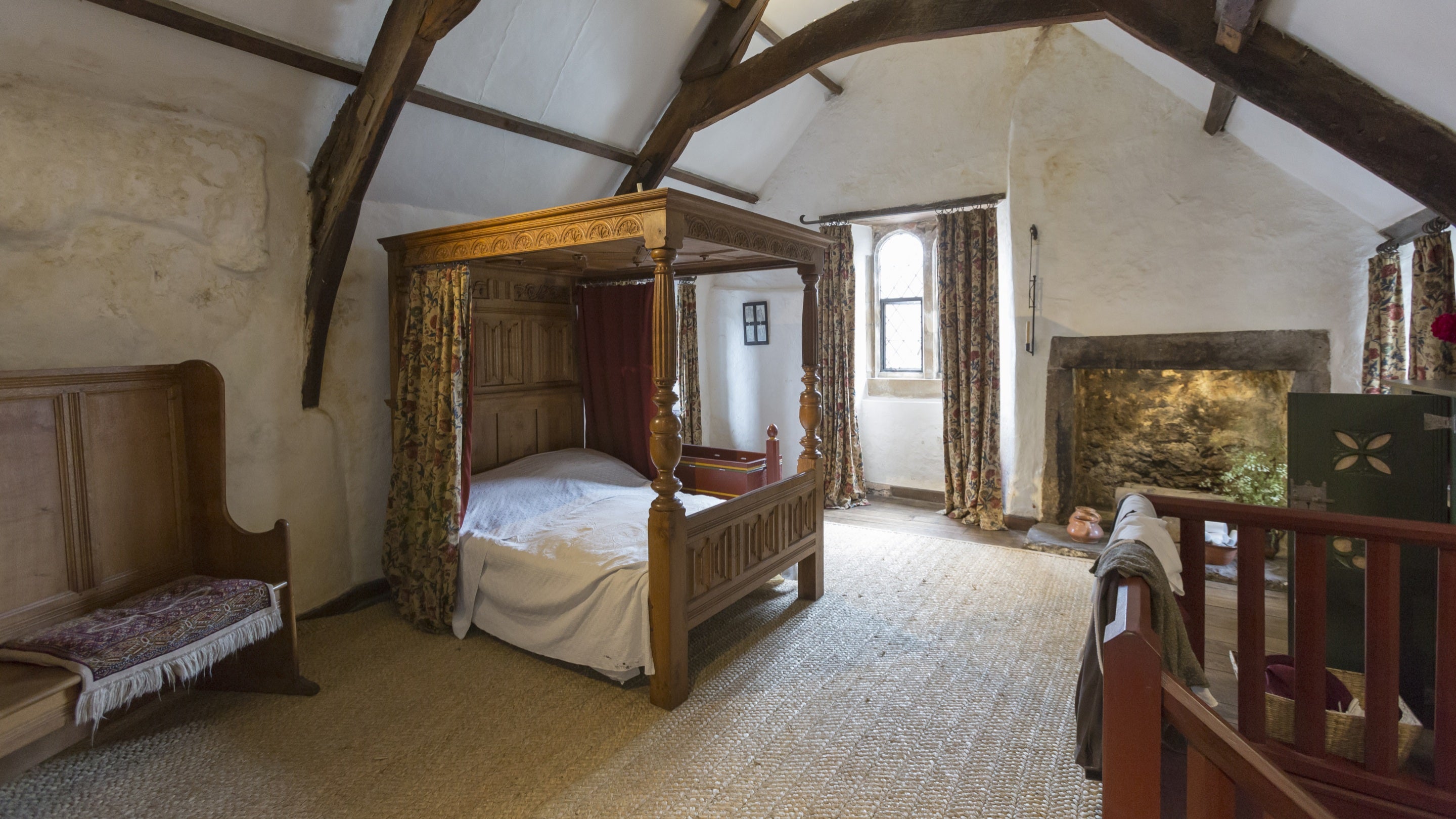 Inside the bedchamber at Tudor Merchant's House, Pembrokeshire, which has a vaulted, wooden-beamed ceiling and a four-poster bed.
