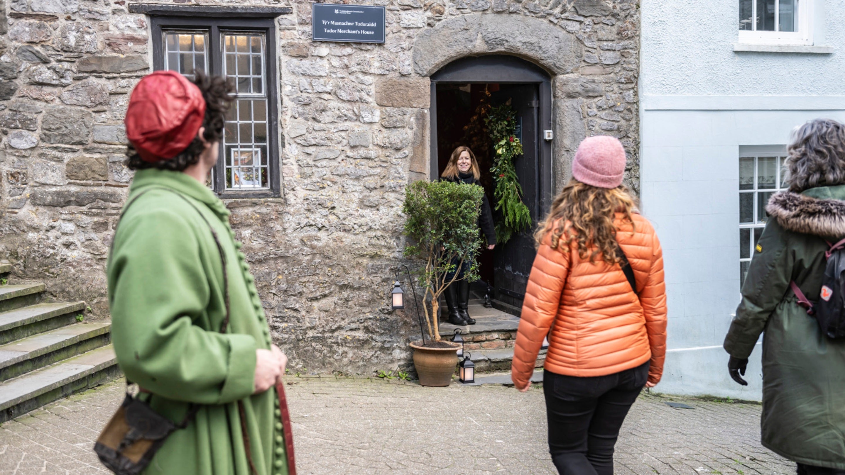 Member of staff and visitors walking toward the entrance of the Tudor Merchant’s House Pembrokeshire