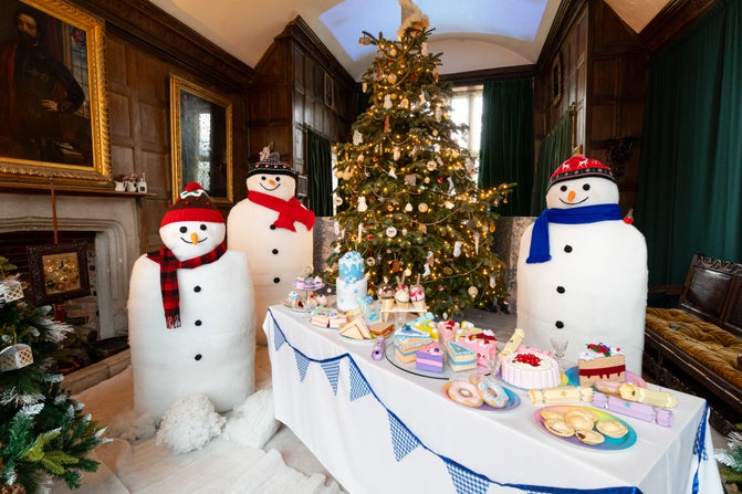 Three model snowmen surround a Christmas tree with a Christmas feast laid out on a table in the Great Parlour at Baddesley Clinton, Warwickshire