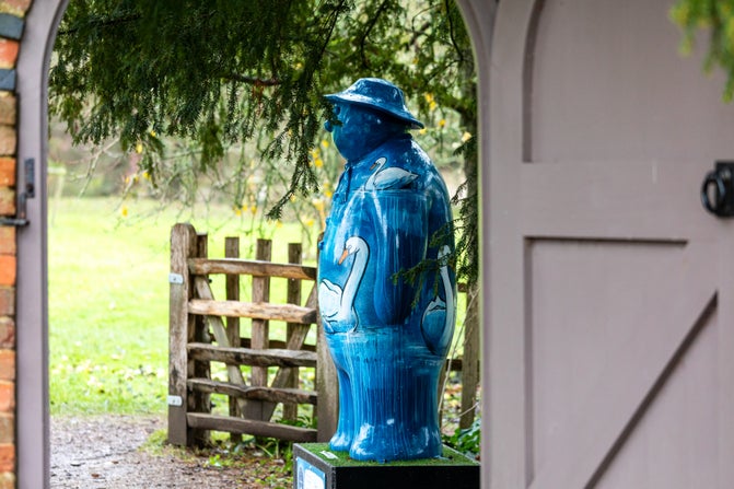A blue-painted Snowman™ covered in swans is seen through a doorway in the gardens at Baddesley Clinton, Warwickshire