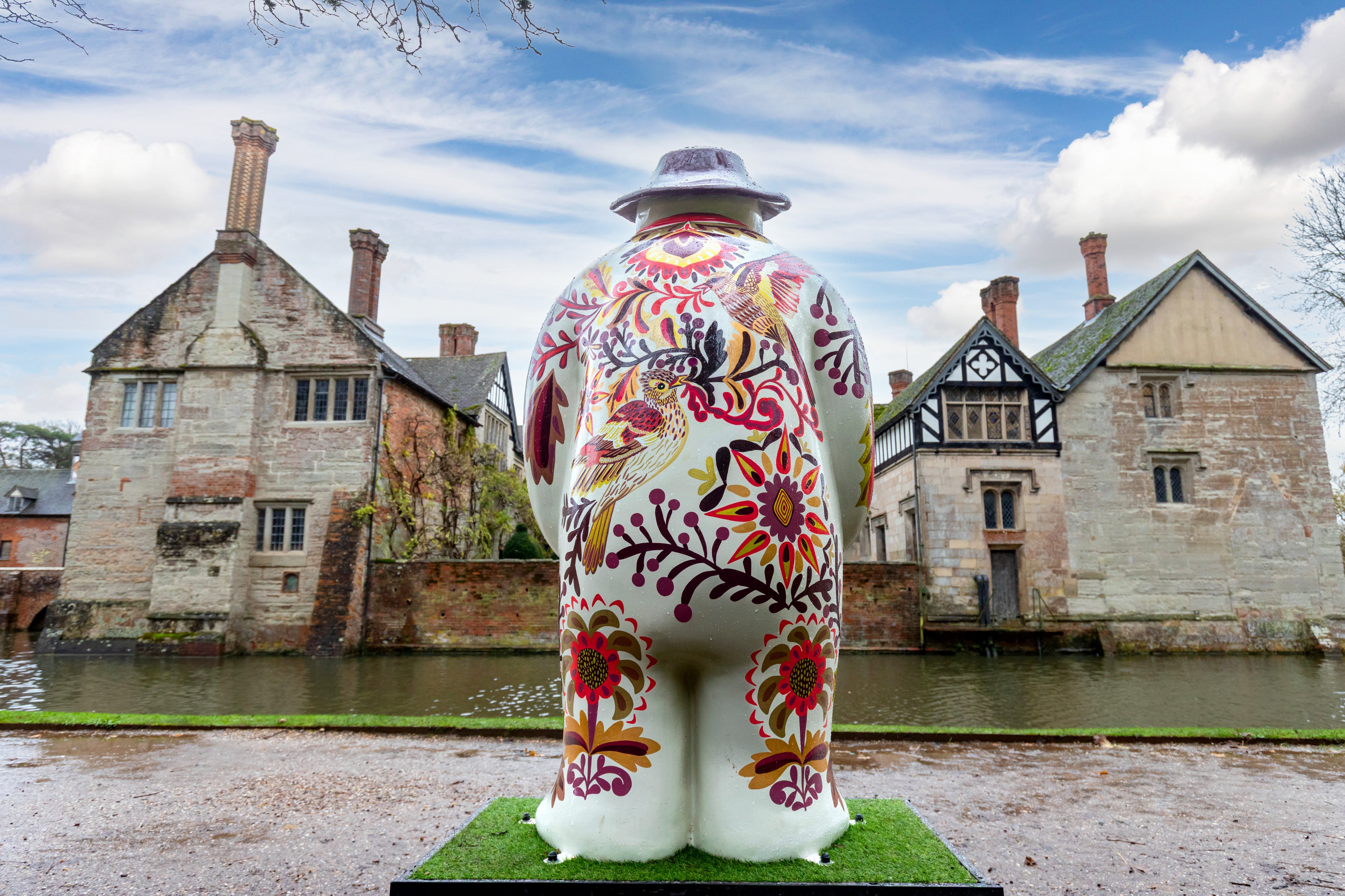 A back view of a colourful Snowman™ looking out over the moat at Baddesley Clinton, Warwickshire