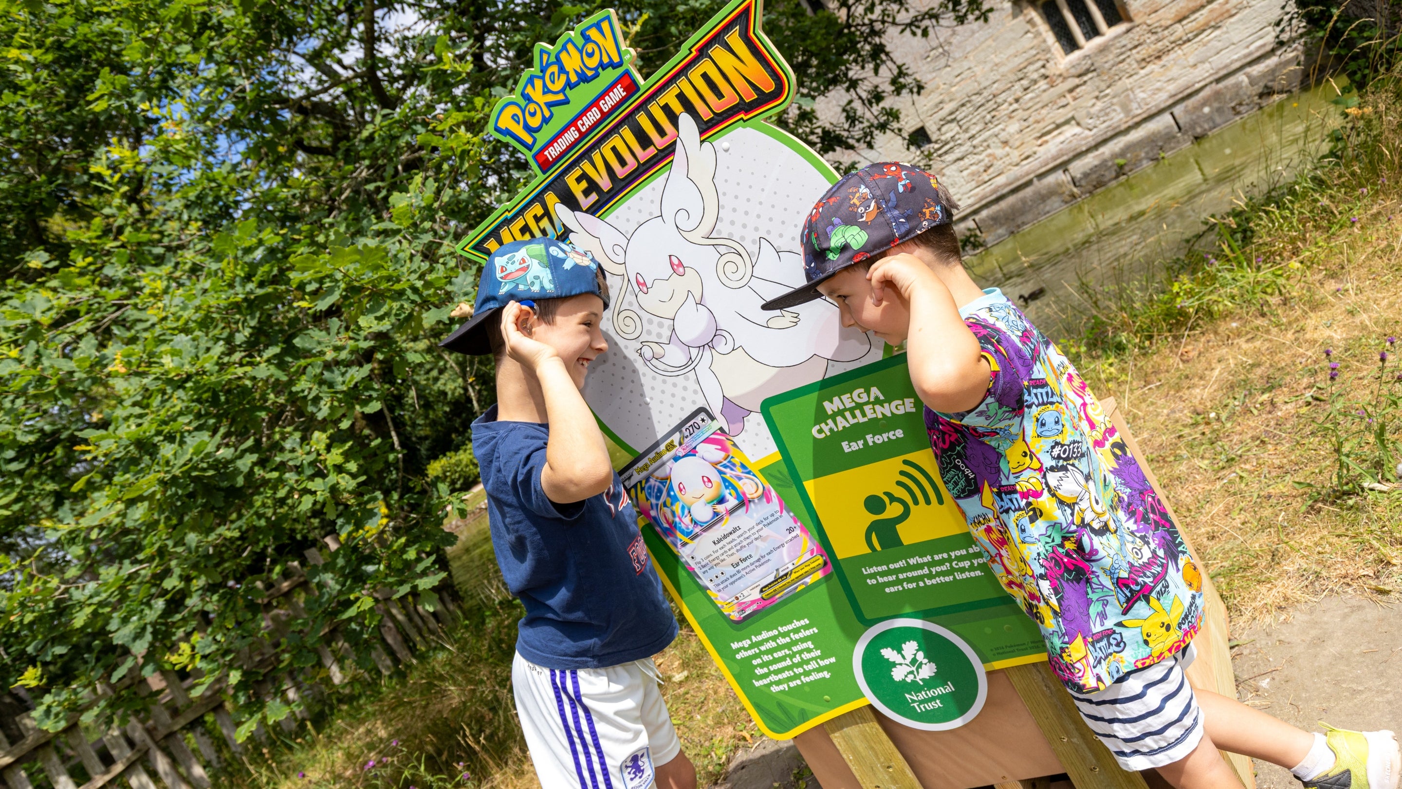 Two boys posing by the sign for the Pokémon Trail at Baddesley Clinton, Warwickshire