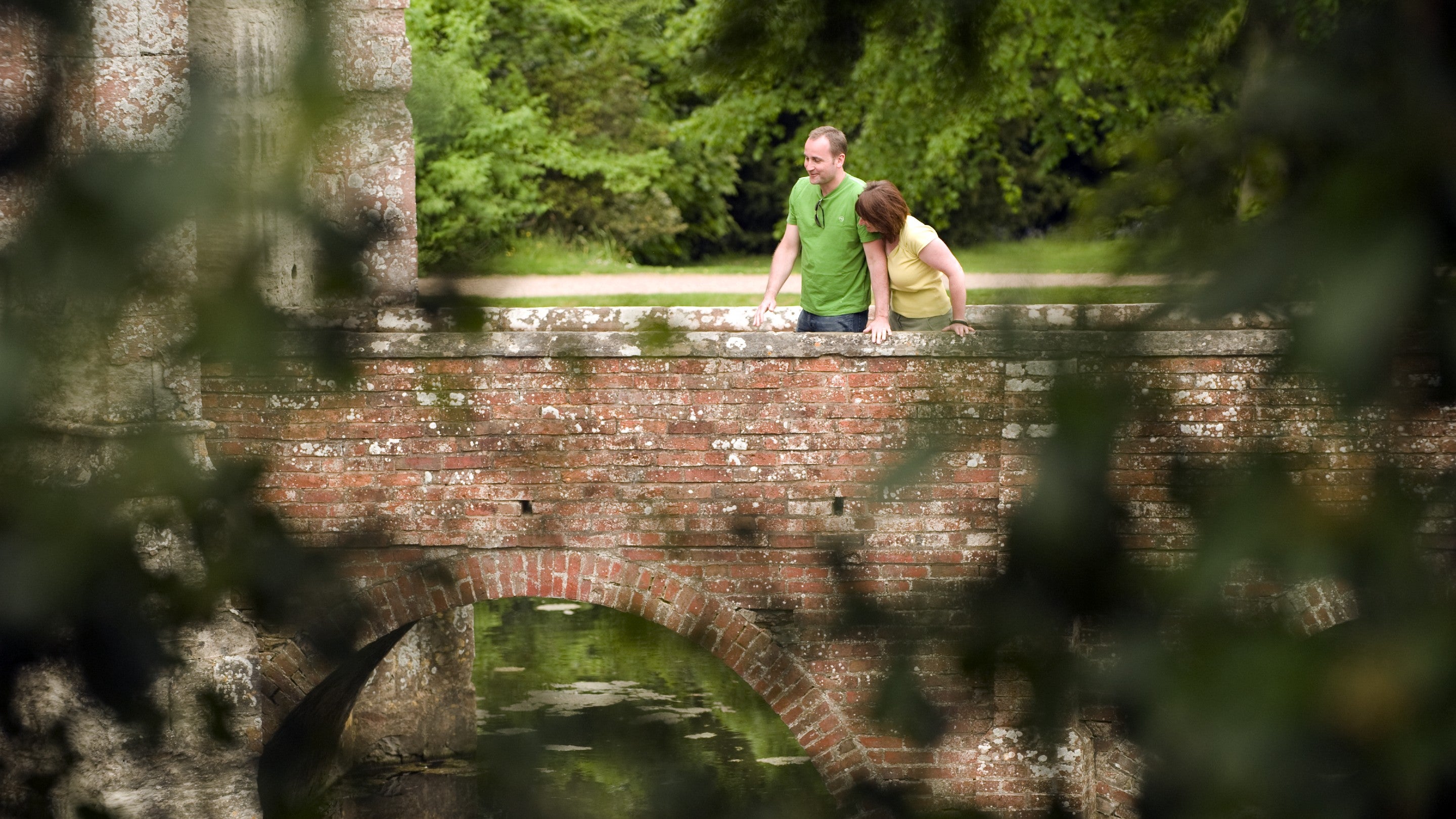 A couple looking over the bridge across the moat at Baddesley Clinton, Warwickshire