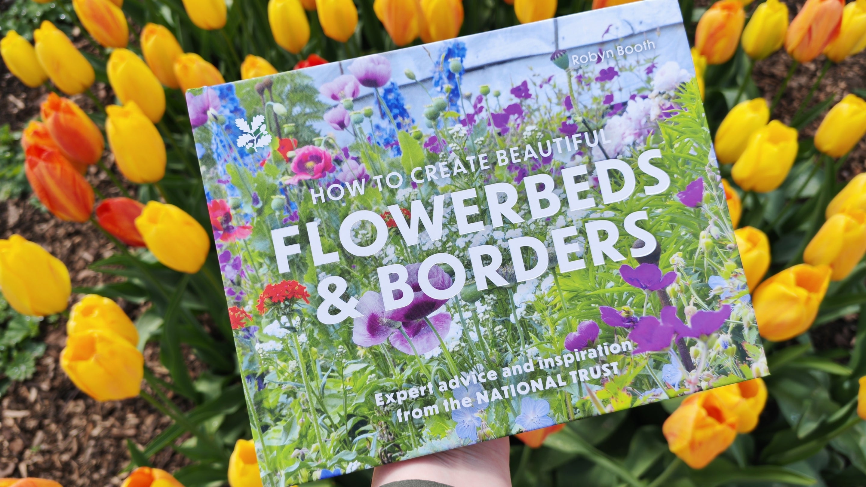 "Flowerbeds & Borders", a new book by Senior Gardener, Robyn Booth, being displayed among a clump of beautiful tulips