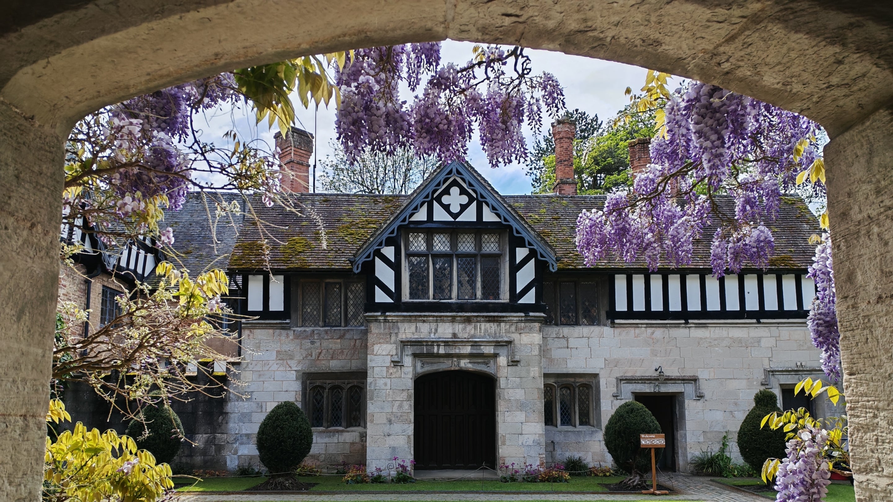 A view through the archway into the courtyard at Baddesley Clinton, Warwickshire, with a curtain of wisteria blooms.