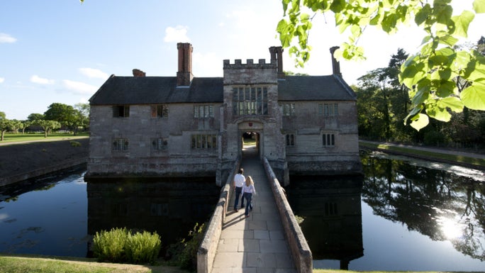 Visitors on the bridge across the moat at Baddesley Clinton, Warwickshire