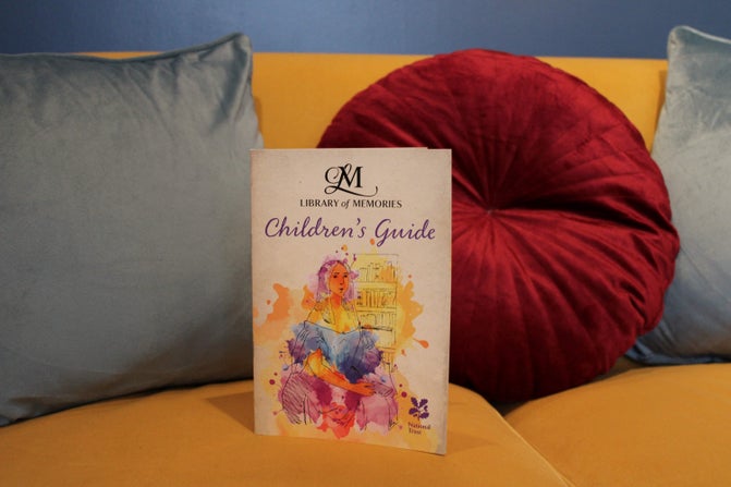 A colourful Children's Guide for the Library of Memories stands on a yellow sofa