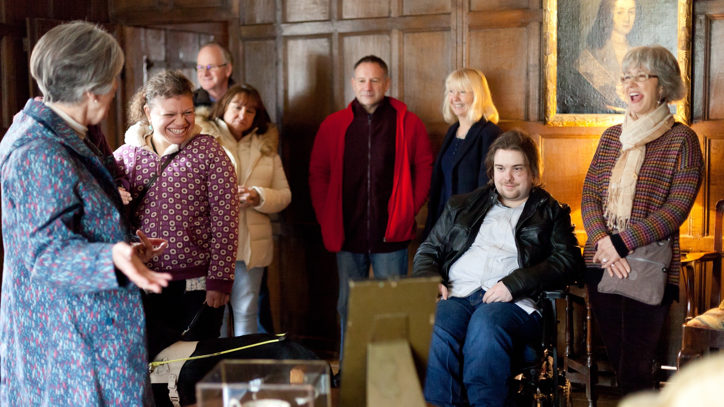 A group of visitors enjoying a guided tour at Packwood House, Warwickshire, in a room with wooden panelling.