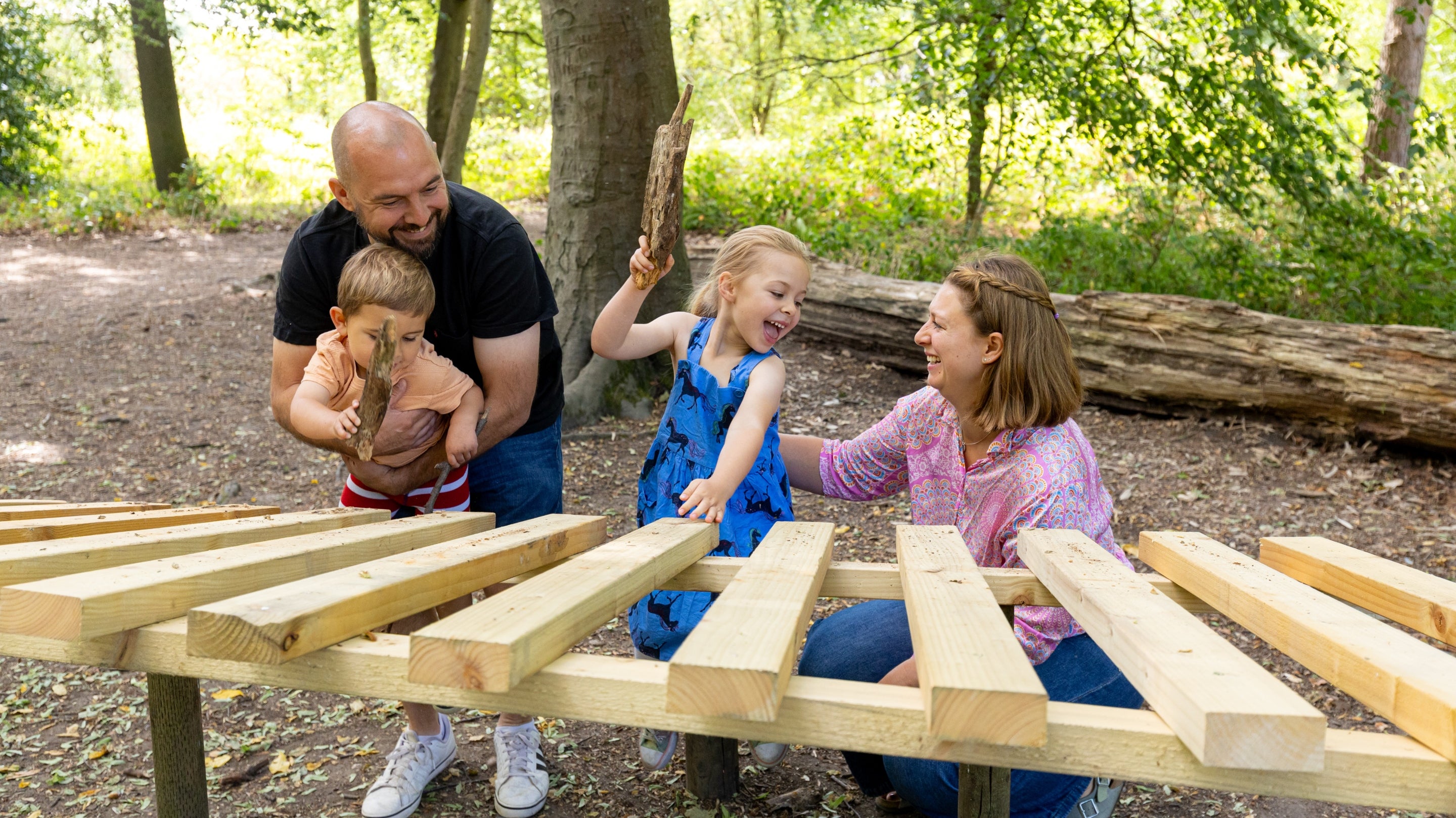 A family having fun on a huge xylophone in the Welly Walk at Packwood House, Warwickshire