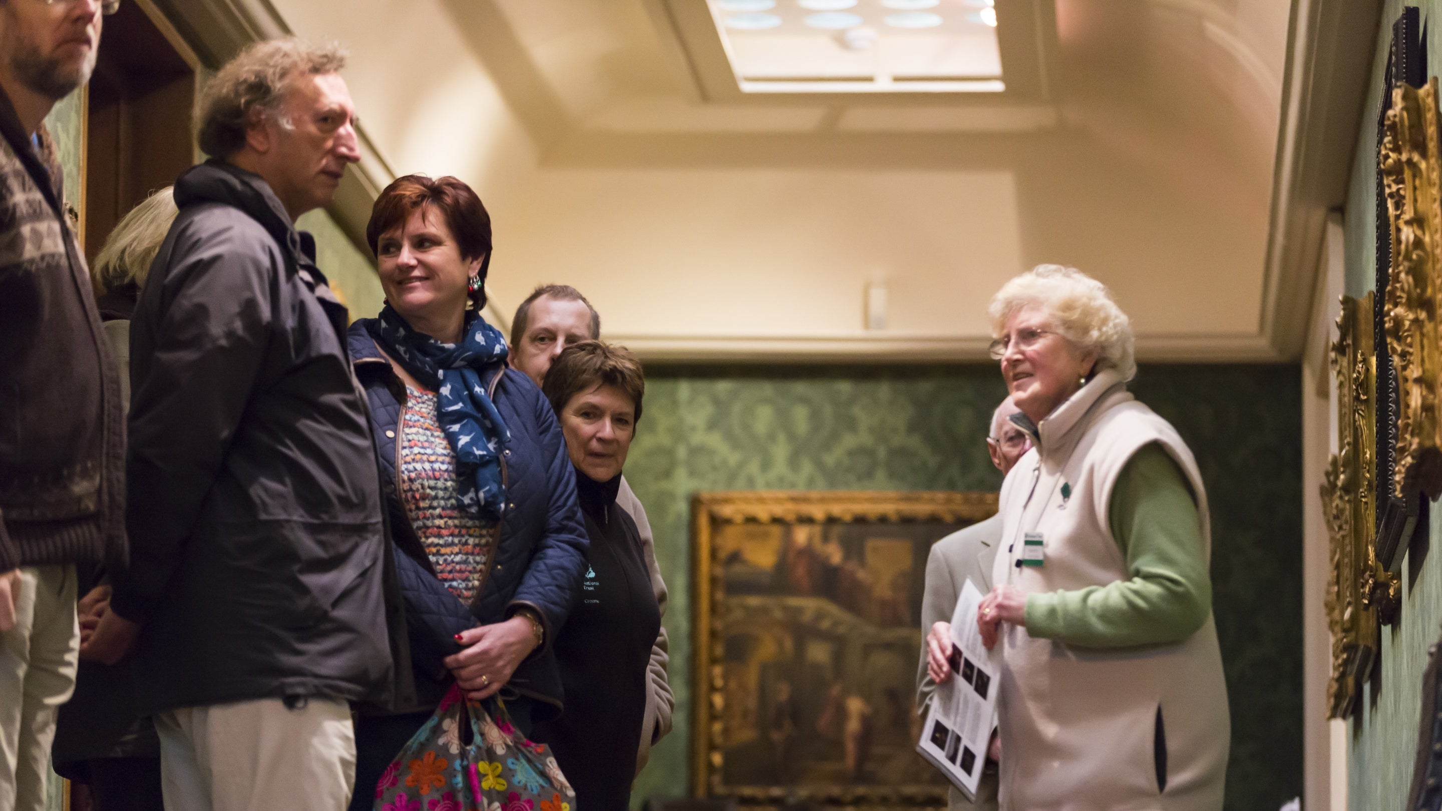 Group of visitors on a guided tour in the Picture Gallery at Upton House and Gardens, Warwickshire