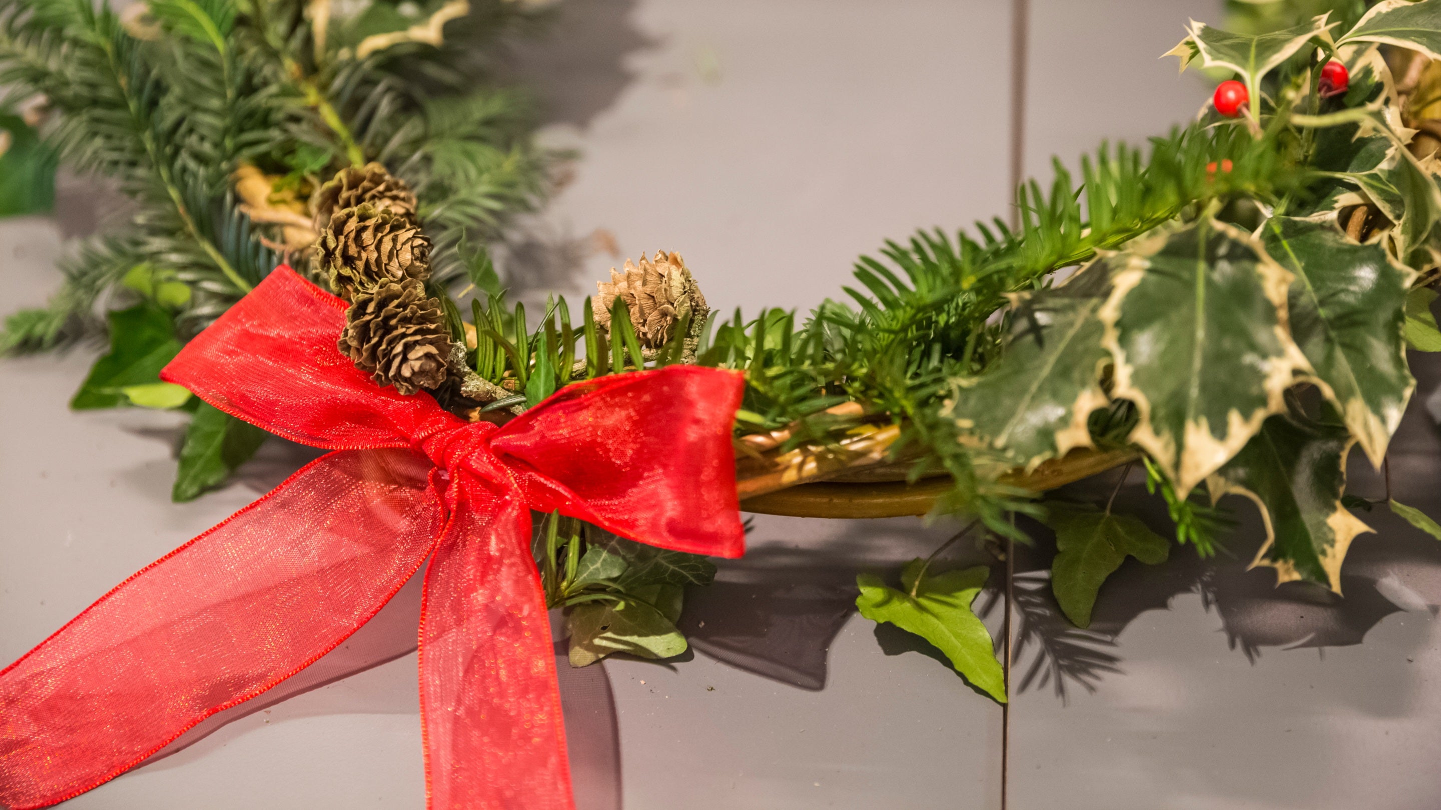 A close up of a Christmas wreath with red bow and greenery