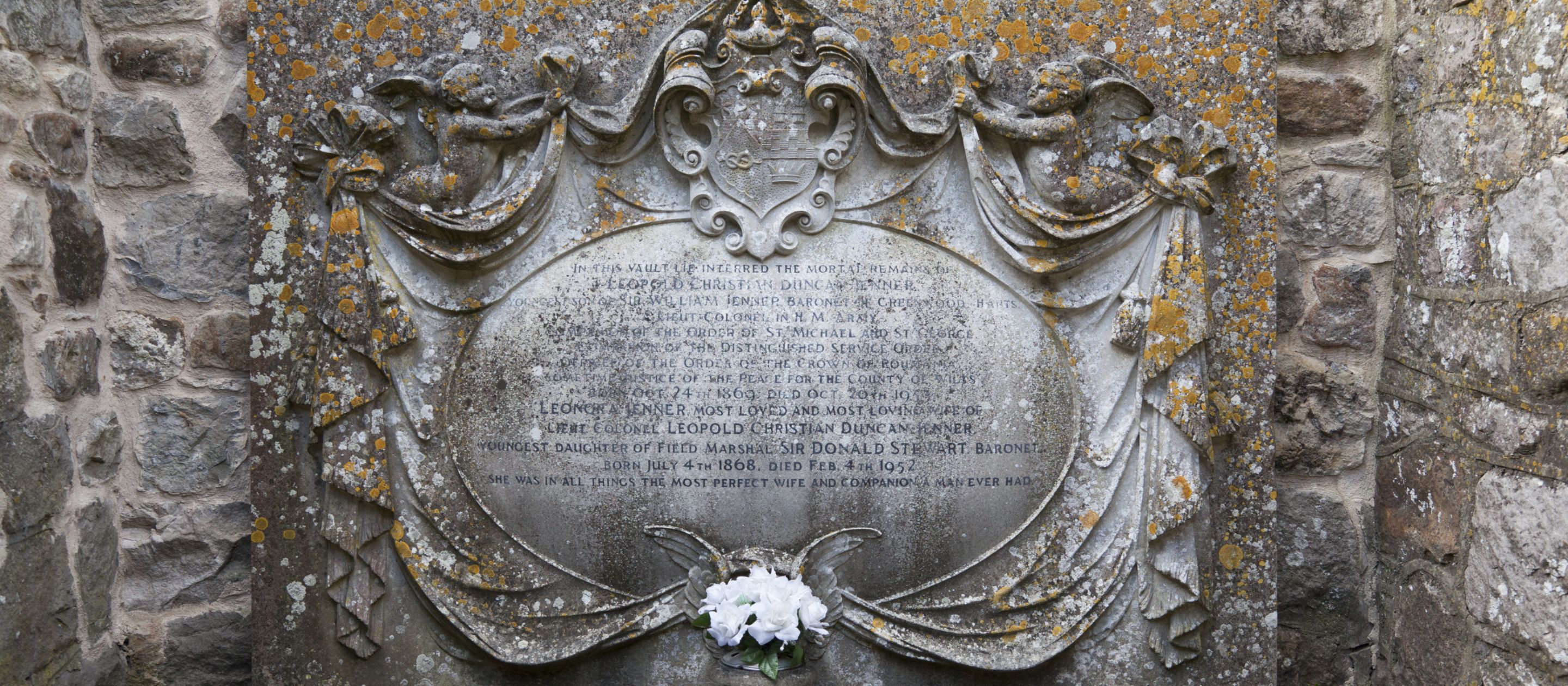 A close up of a large engraved stone memorial plaque dedicated to Leopold and Nora Jenner