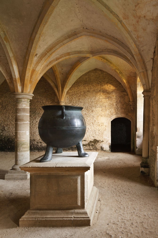 The bell metal Cauldron stands on a stone plinth in the medieval Warming Room of Lacock Abbey