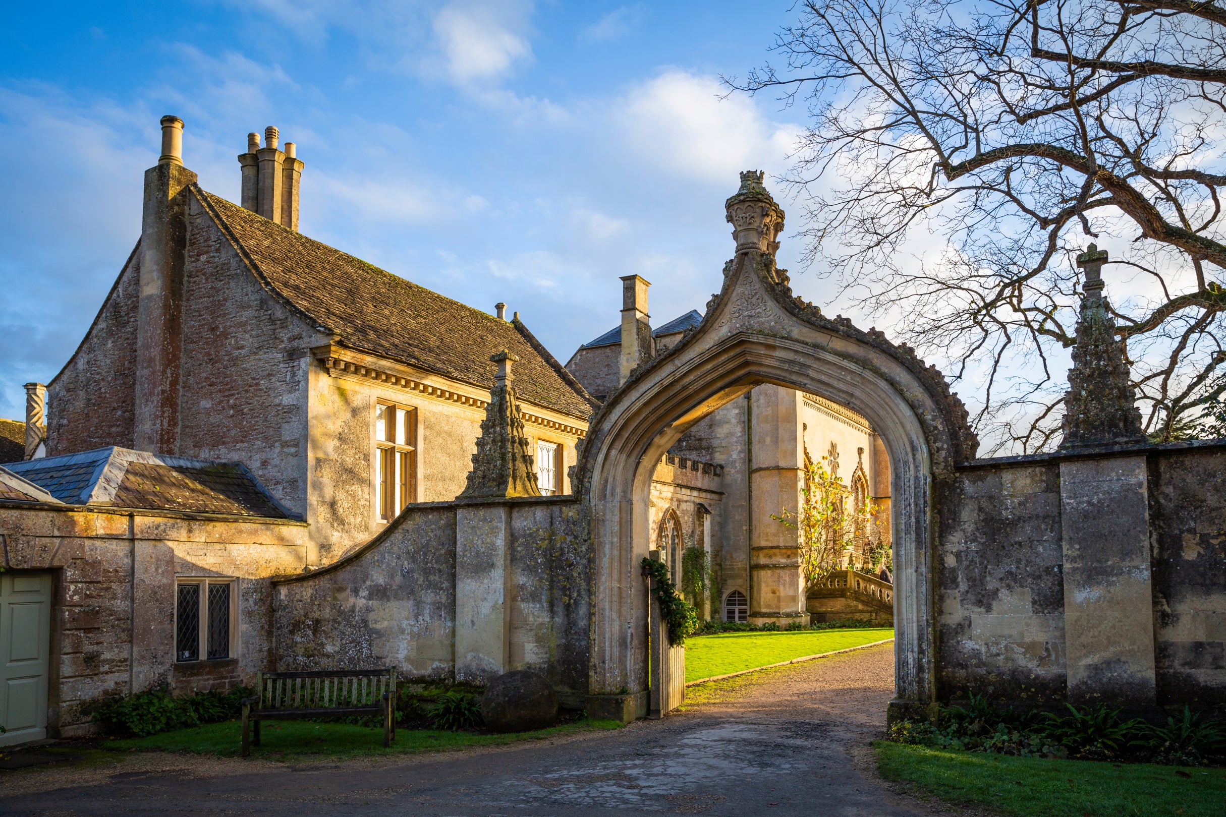 Morning sun shining through a view of the West front through the Gothick arch at Lacock Abbey, Wiltshire