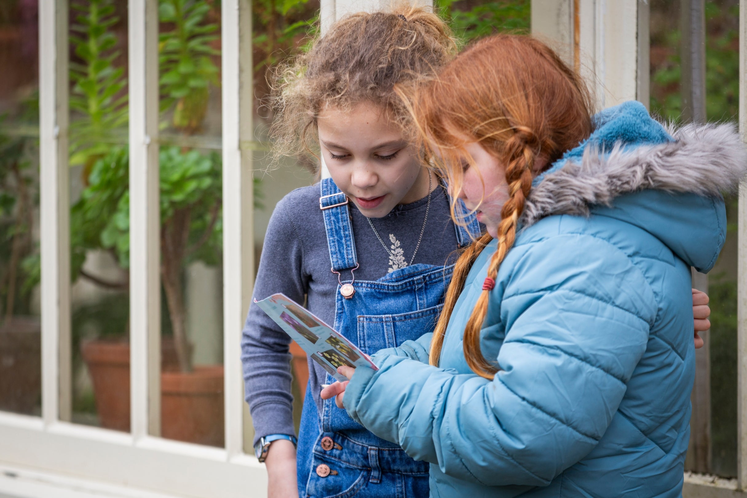 Two children in the Botanic Garden at Lacock look at a flower spotter sheet