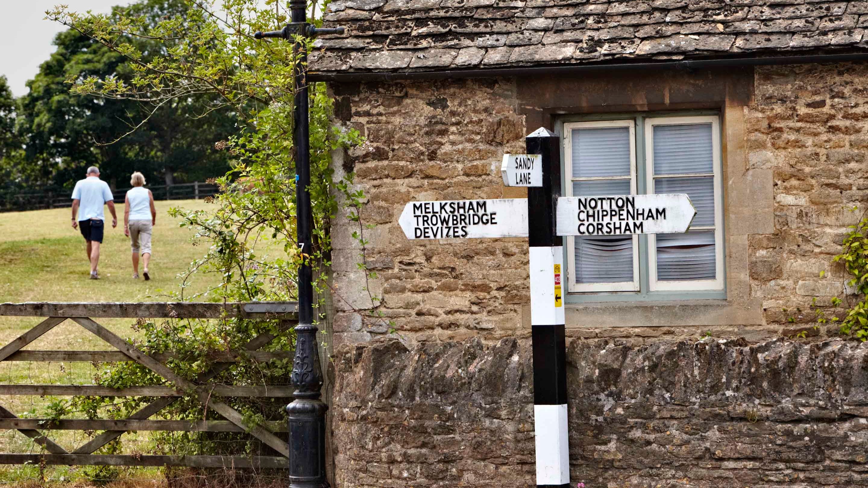 Two people walking through a field in Lacock village in Wiltshire
