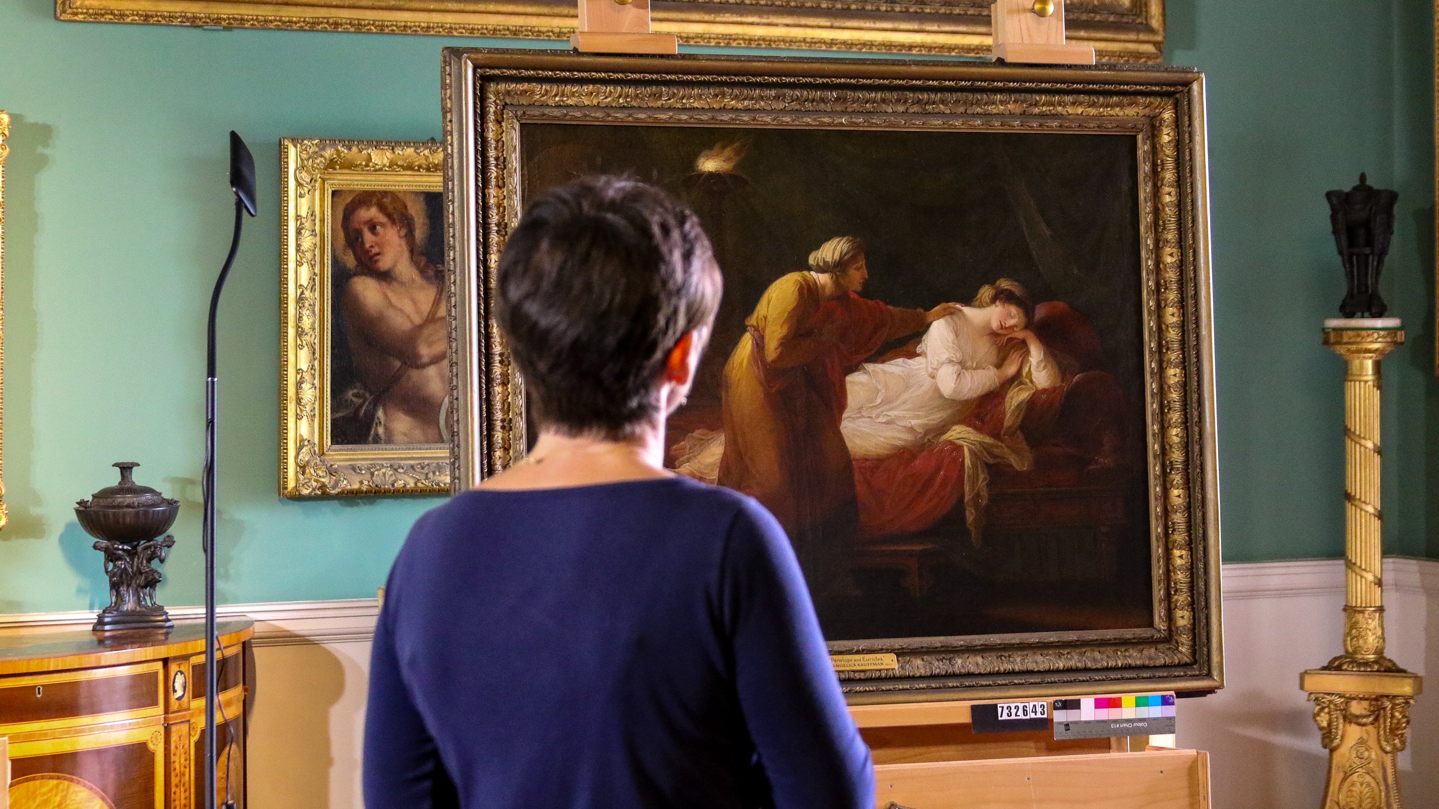 Conservator April Johnson looks over at the fine oil painting 'Penelope and Euriclea' by Angelica Kauffman displayed inside the picture gallery, Stourhead, Wiltshire