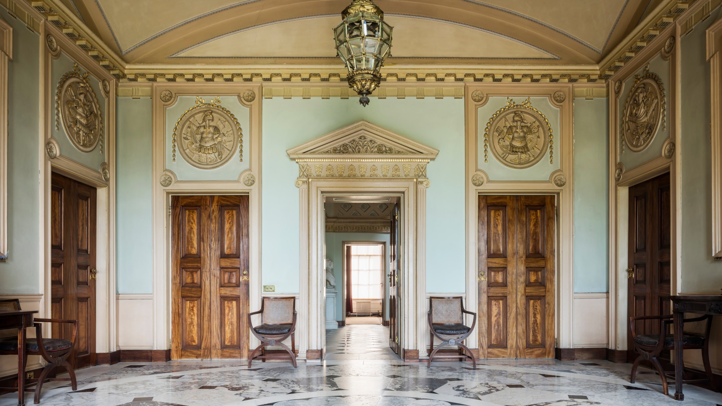 The interior of the Marble Hall at Berrington Hall, Herefordshire, with its decorative marble floor, wooden doors and ornate plasterwork.